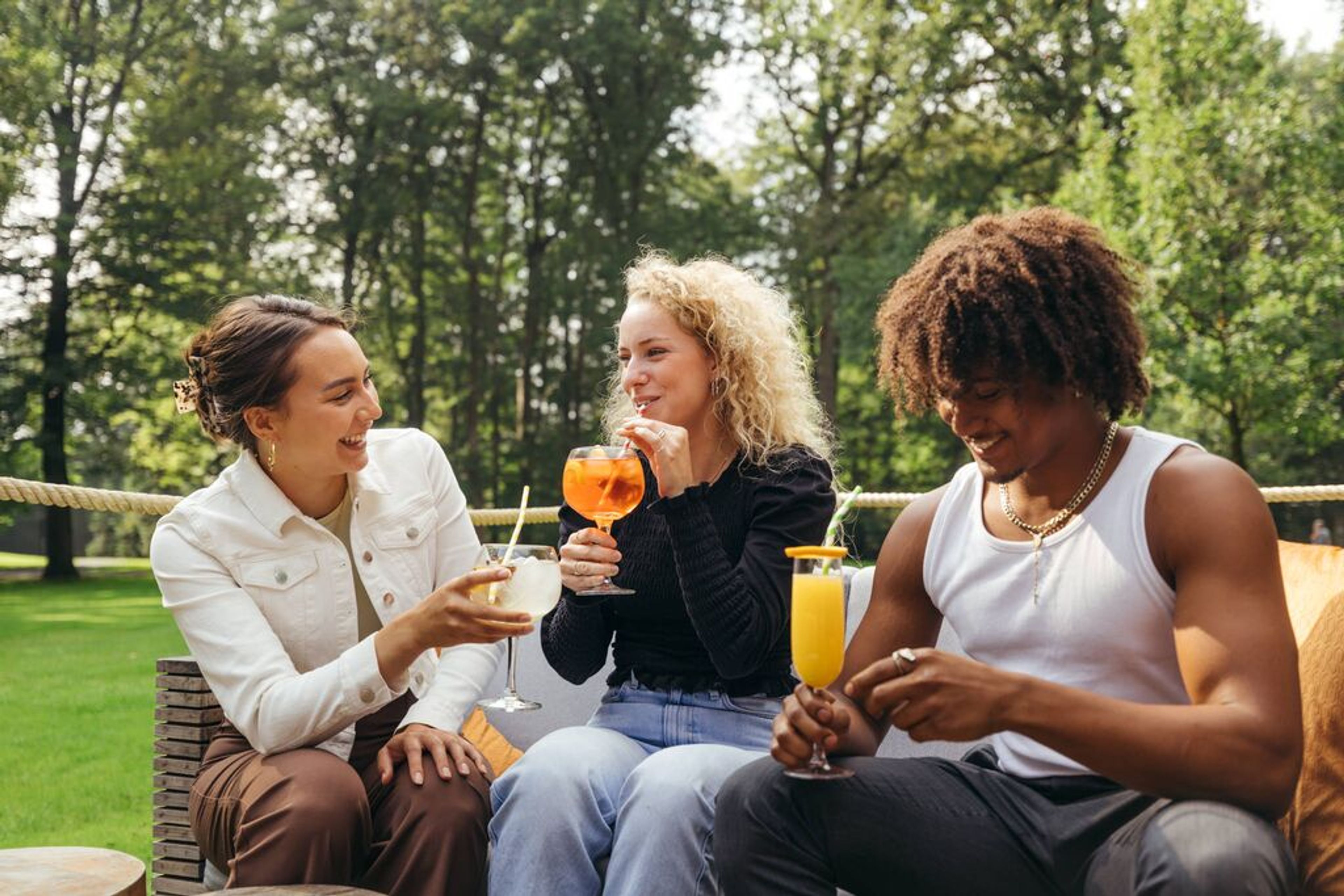 Drie bezoekers drinken een drankje buiten in het groen