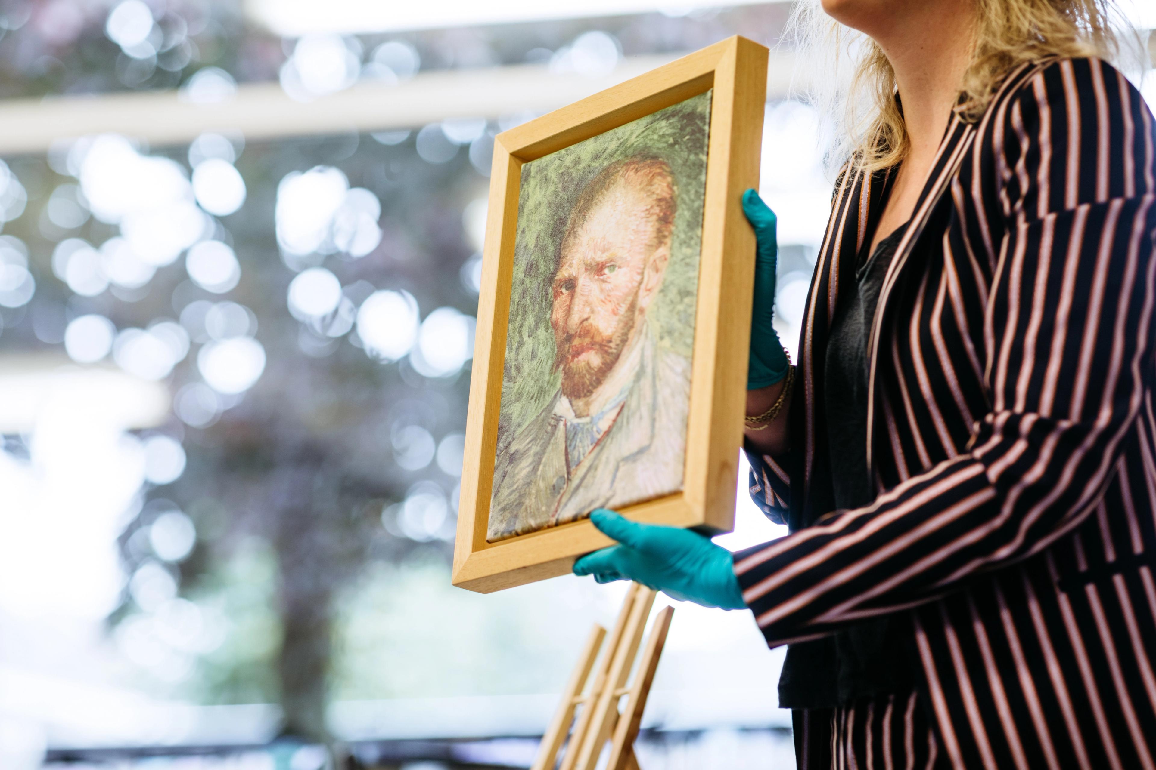 Museumdocent houdt een reproductie van 'Zelfportret' van Vincent van Gogh vast. 
