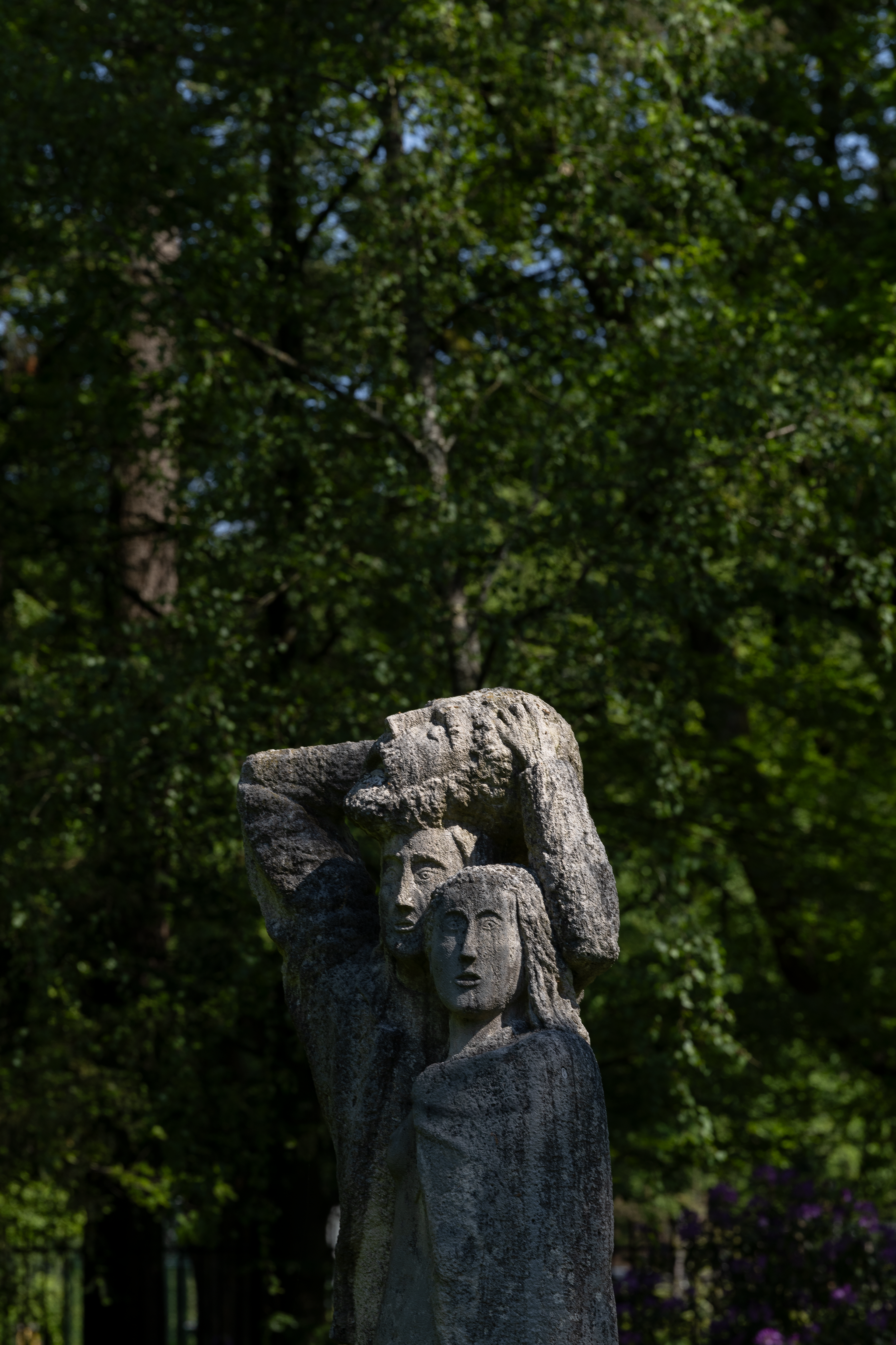 Arturo Martini, _Giuditta e Oloferne_, 1932-1933 Beeldhouwwerk van een persoon met handen achter hoofd, gemaakt van ruwe steen en geplaatst in een groene buitenomgeving met bomen op de achtergrond
