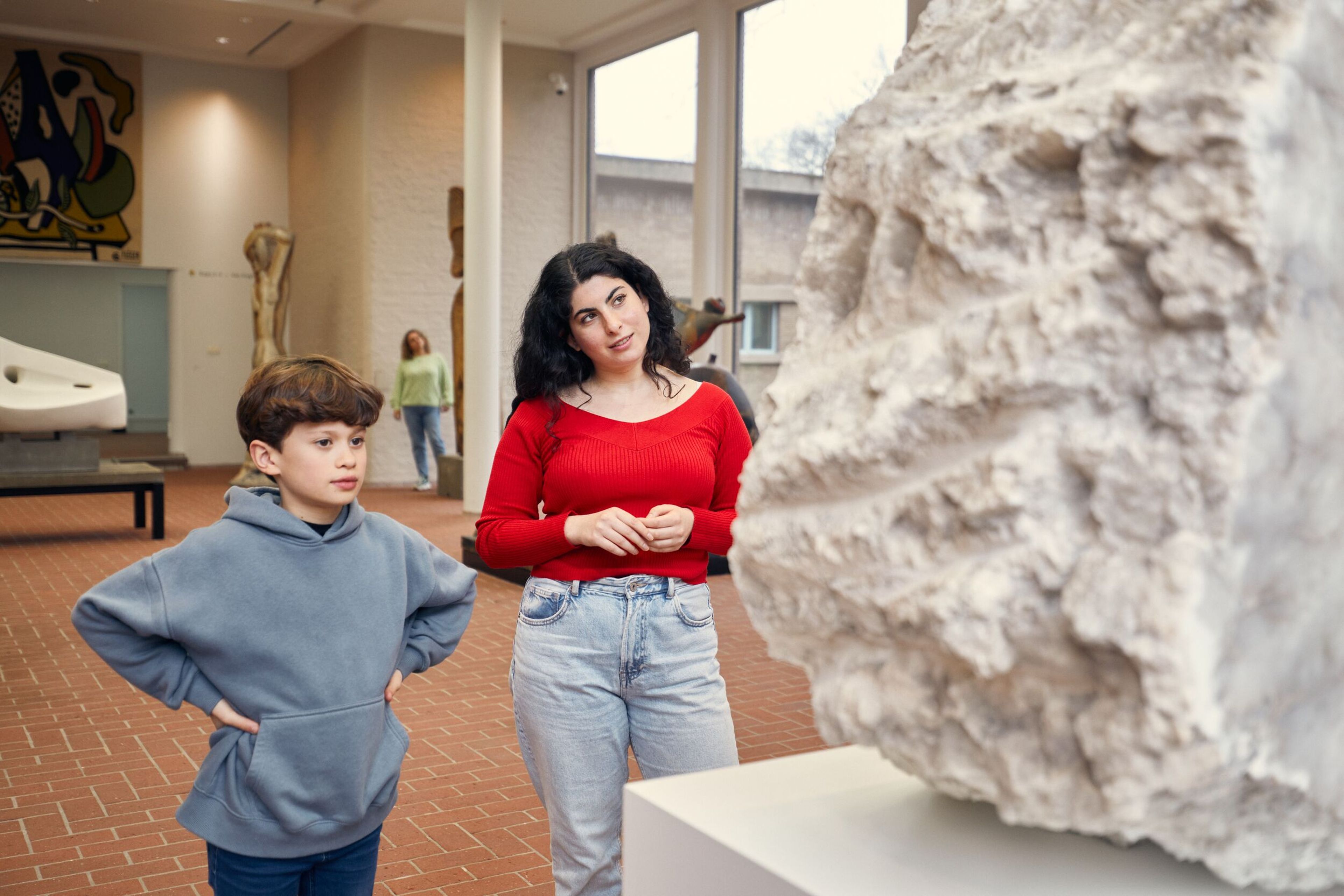 Een volwassene en een kind staan bij een marmeren kunstwerk met ruwe zijkant