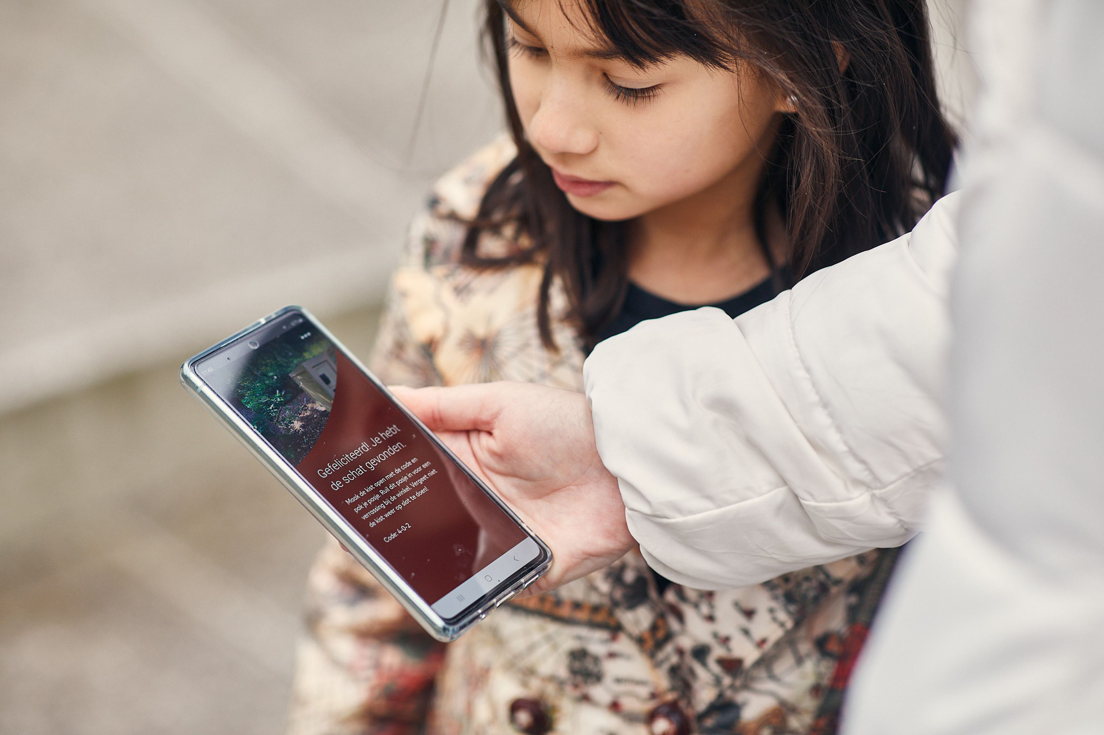 Foto van persoon die een smartphone vasthoudt, op het scherm zie de de geo route app
