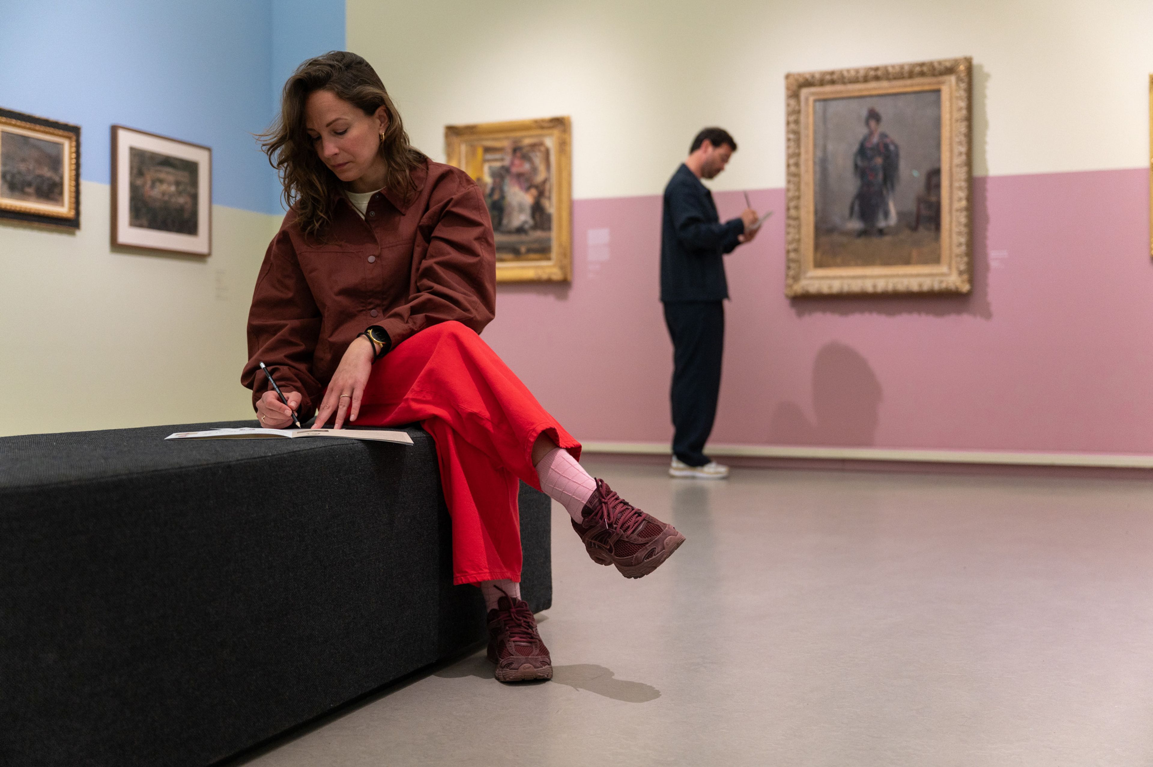 Bezoeker tekent op een bankje in de tentoonstelling 'Het Europa van Isaac Israels'