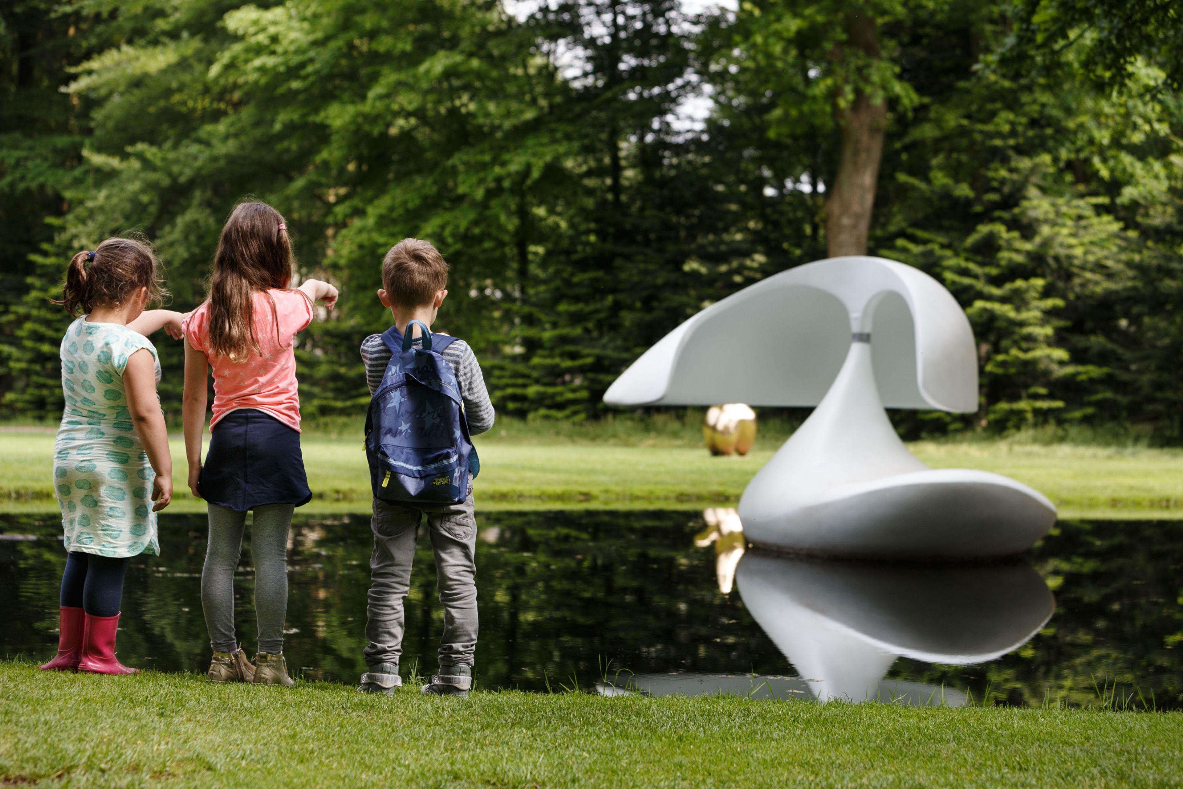 Drie kinderen staan voor een vijver met 'Sculpture flottante, Otterlo', Zwaan
