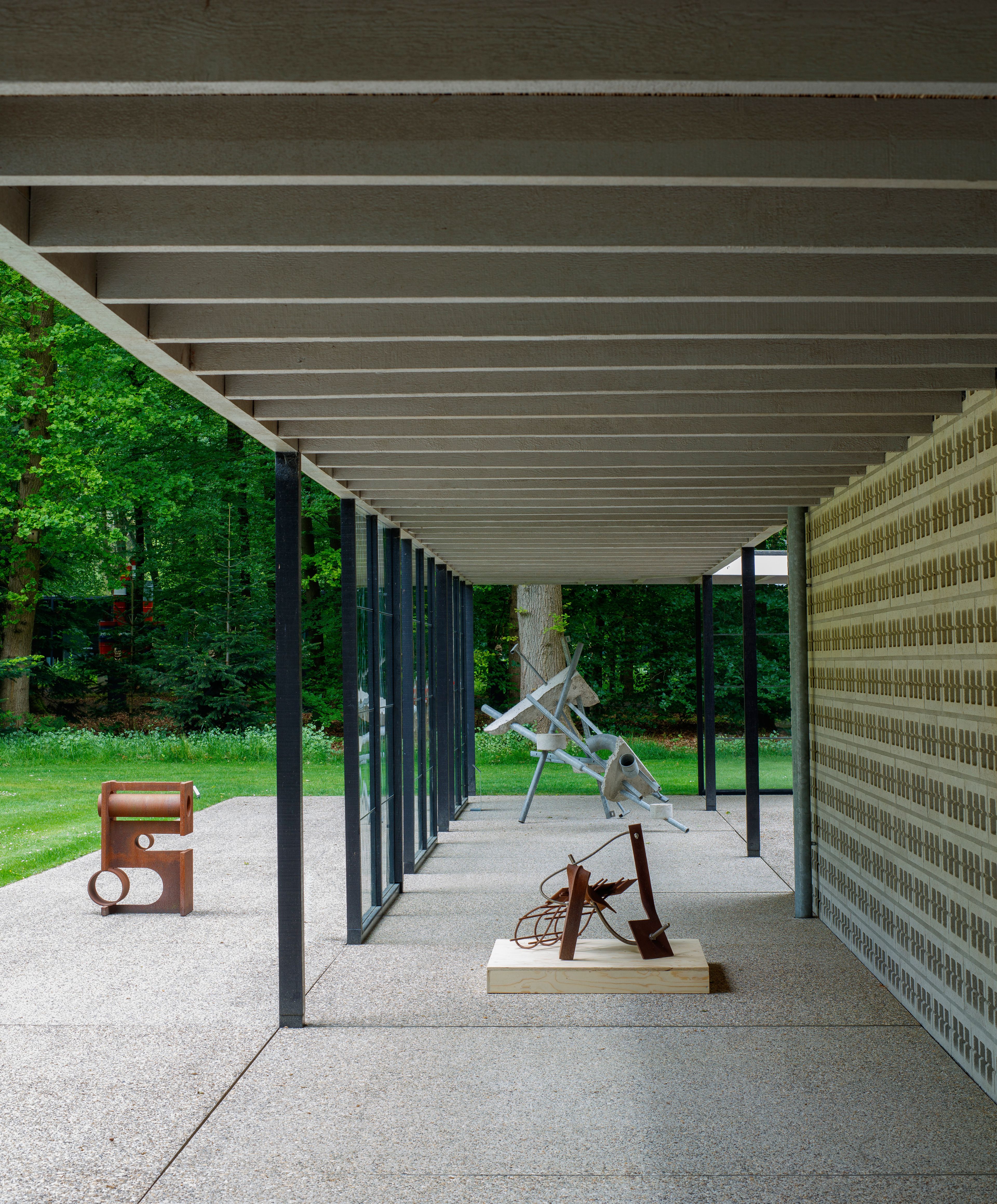 Ruud Kuijer in the Rietveld Pavilion, photo: Rob Versluys Photo of several steel sculptures in a modern pavilion set within a park-like environment. The sculptures have irregular, organic shapes.