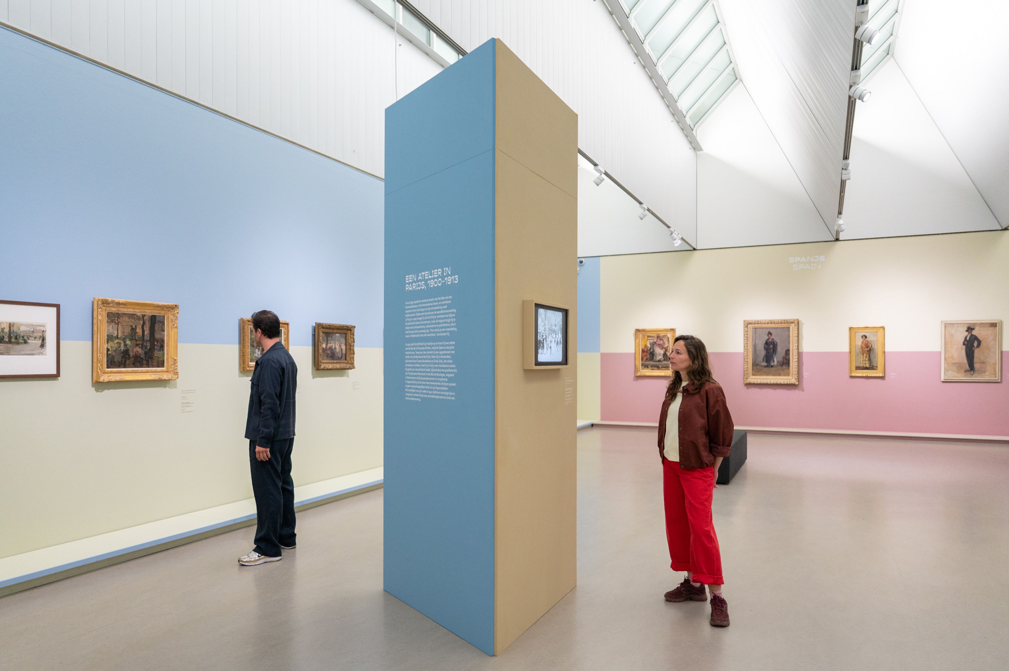 Twee bezoekers in de tentoonstelling, kijken naar de kunst en lezen de tentoonstellingsteksten