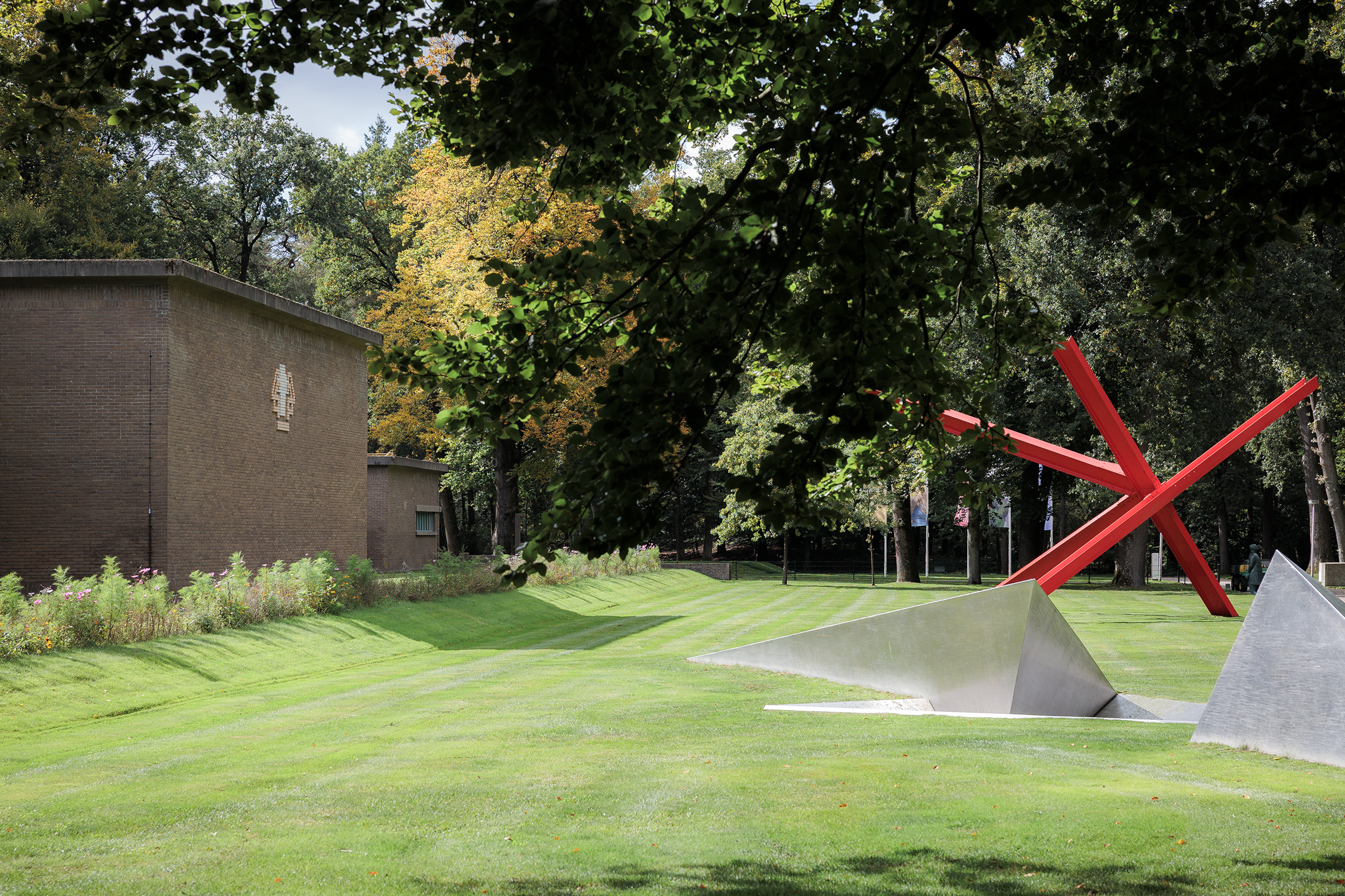 Entree van het Kröller-Müller Museum, met links een gebouw, en rechts een groot rood kunstwerk
