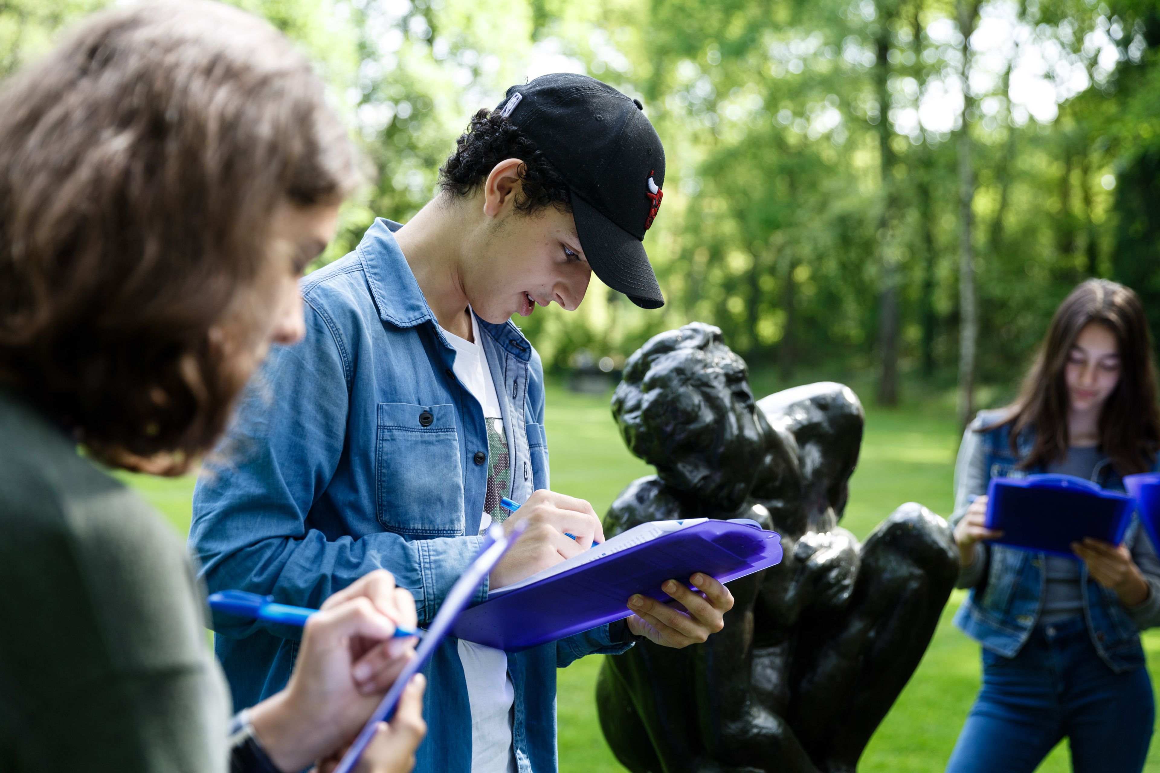 Scholieren werken aan een opdracht in de beeldentuin