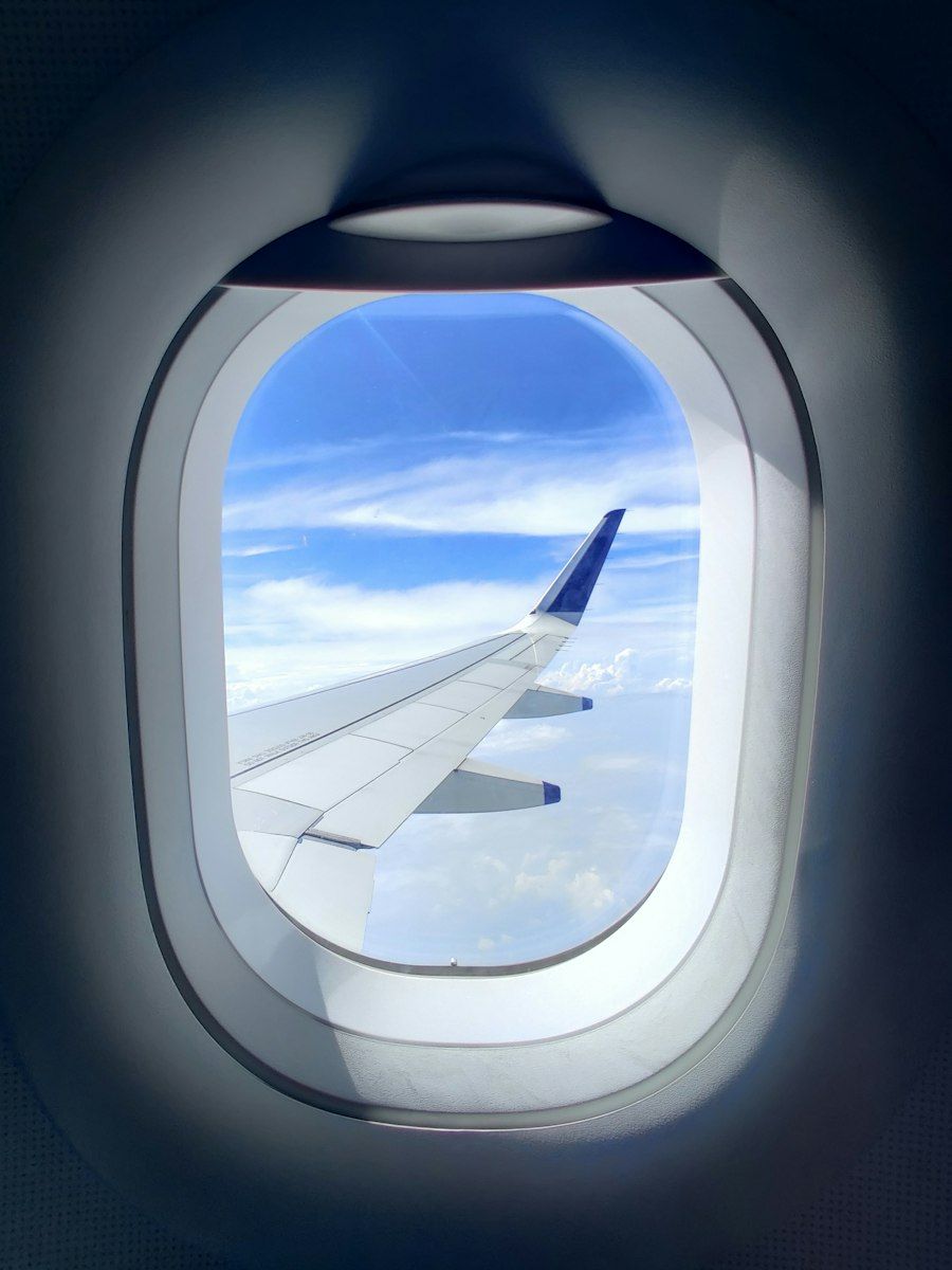 An airplane wing seen through the window, above the clouds