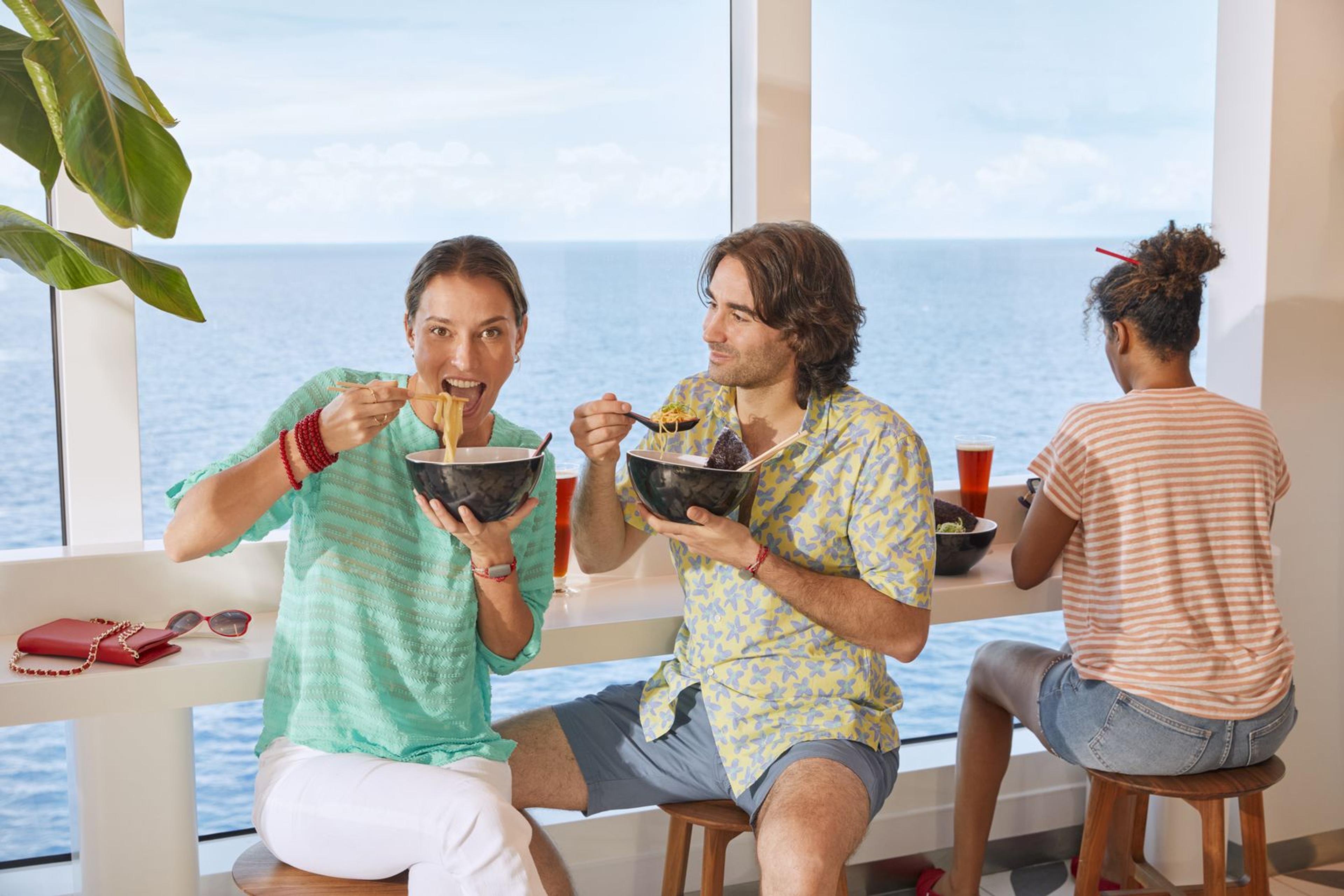 Trois passagers mangent des nouilles au comptoir de The Galley, face à la mer