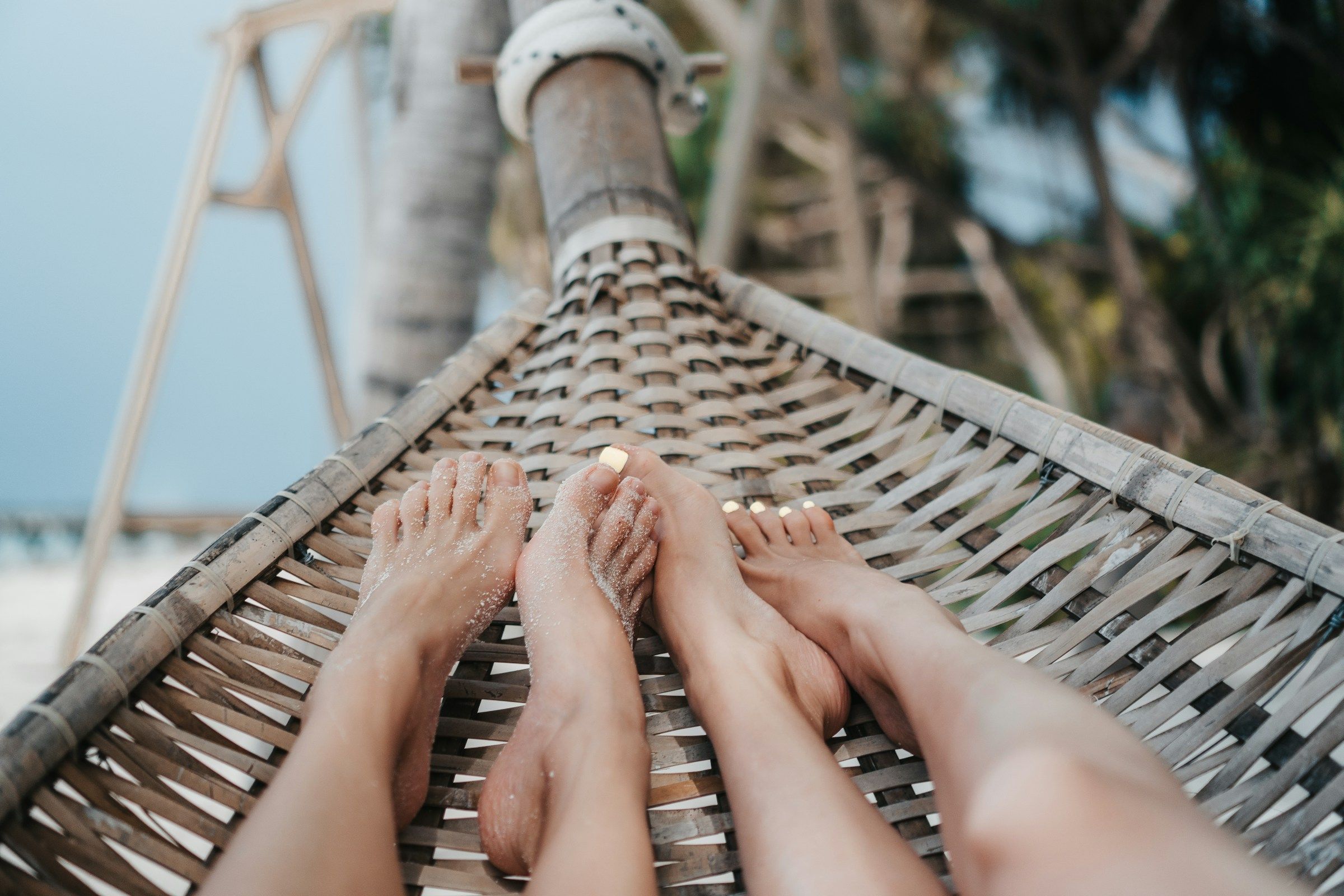 Deux paires de pieds dans un hamac, au bord de la plage