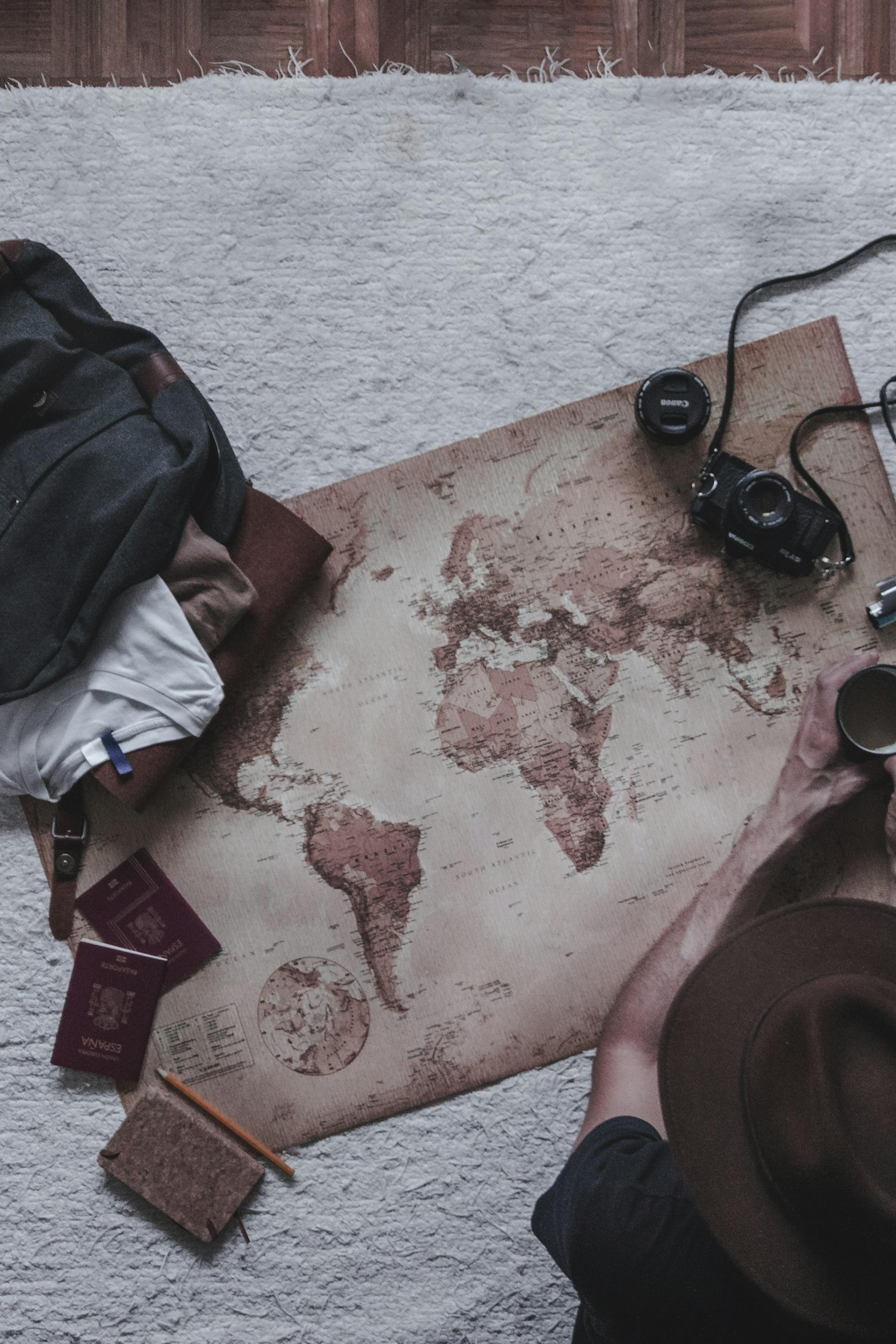 Une main tient une tasse de café à côté d'une carte du monde et d'un appareil photo