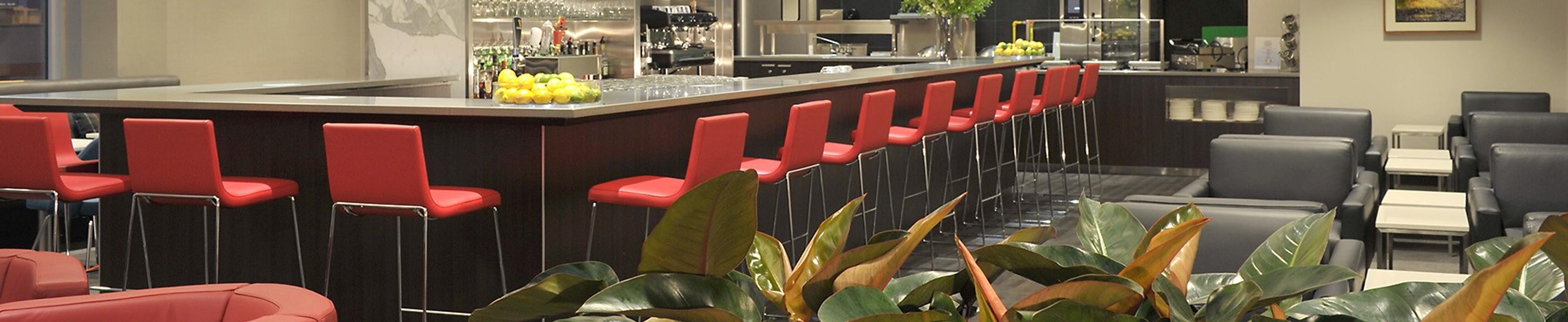 Le bar du salon Feuille d'érable, ses tabourets rouges et ses fauteuils gris