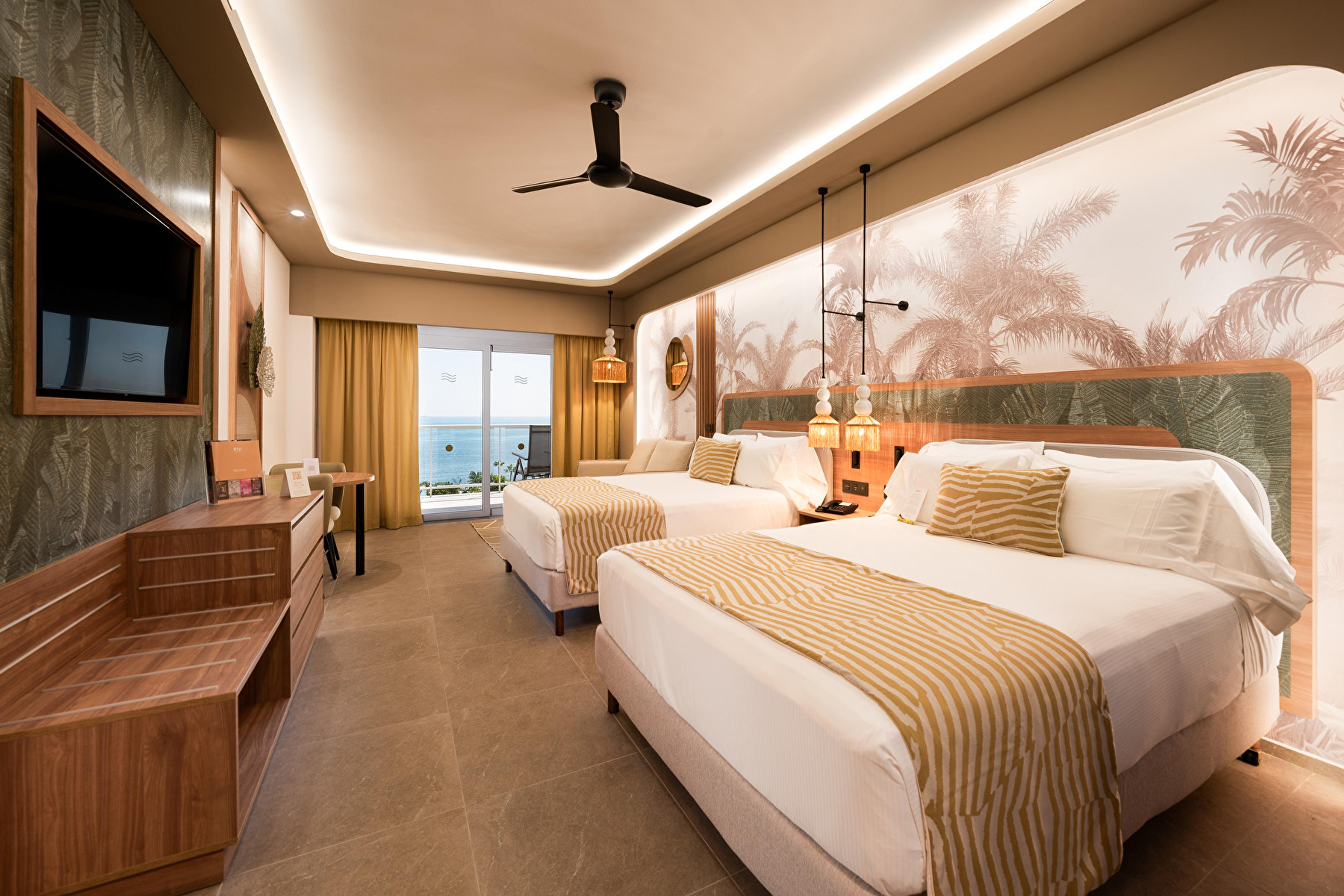 An ocean-view junior suite at the Riu Palace Peninsula, with warm woodwork and natural tones
