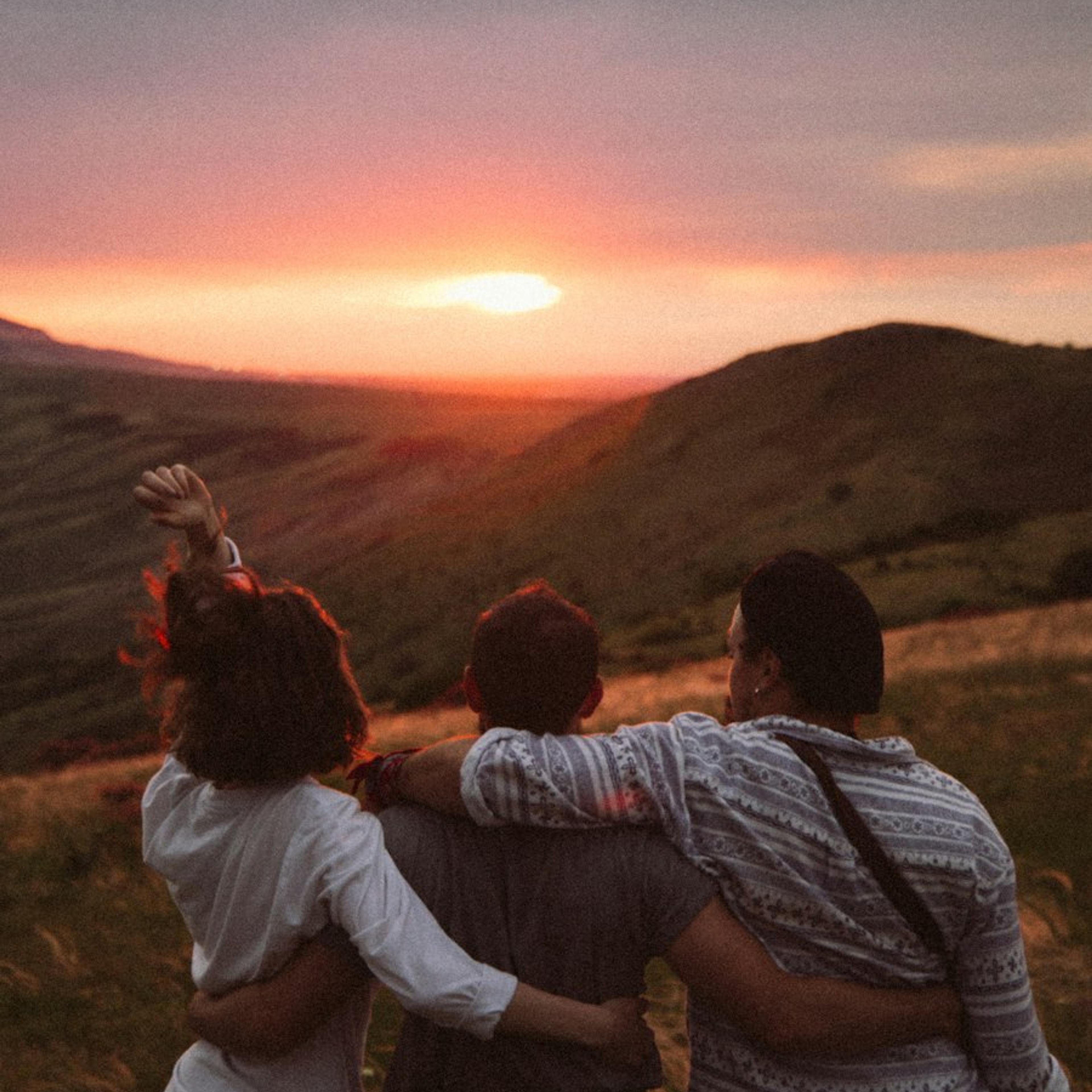 A group of friends arm in arm at sunset