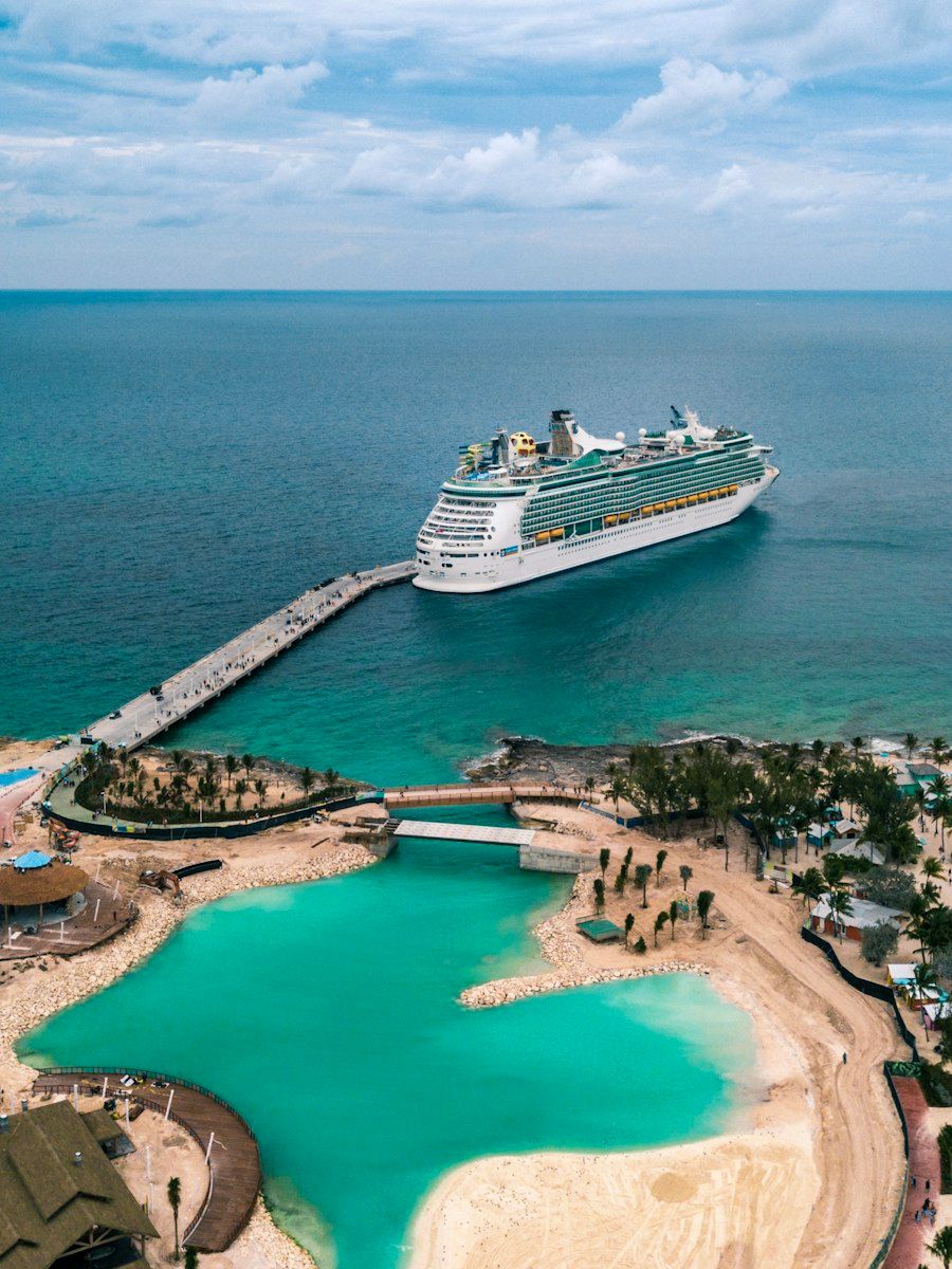 A cruise ship docked by an island with turquoise water