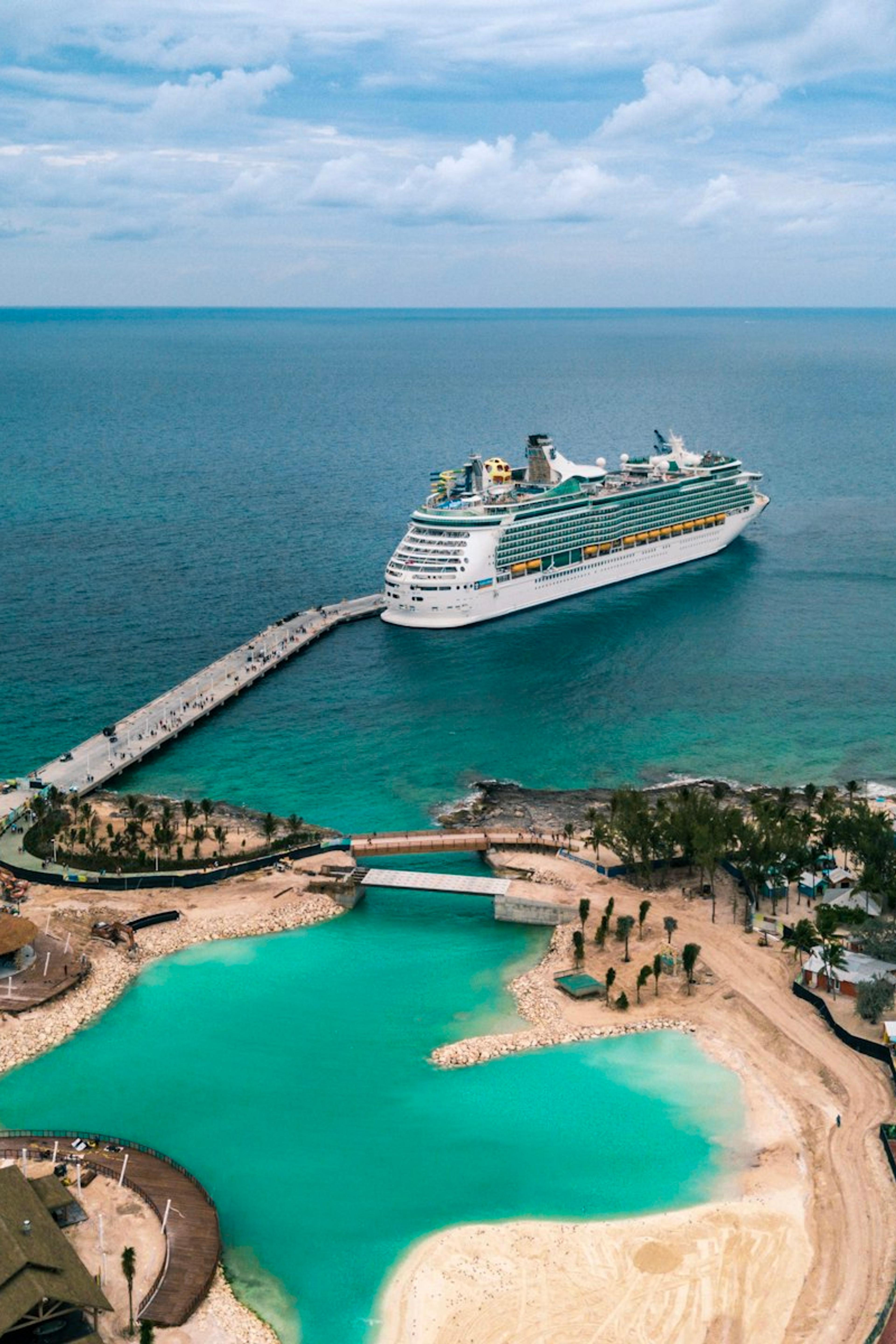 A cruise ship docked by an island with turquoise water