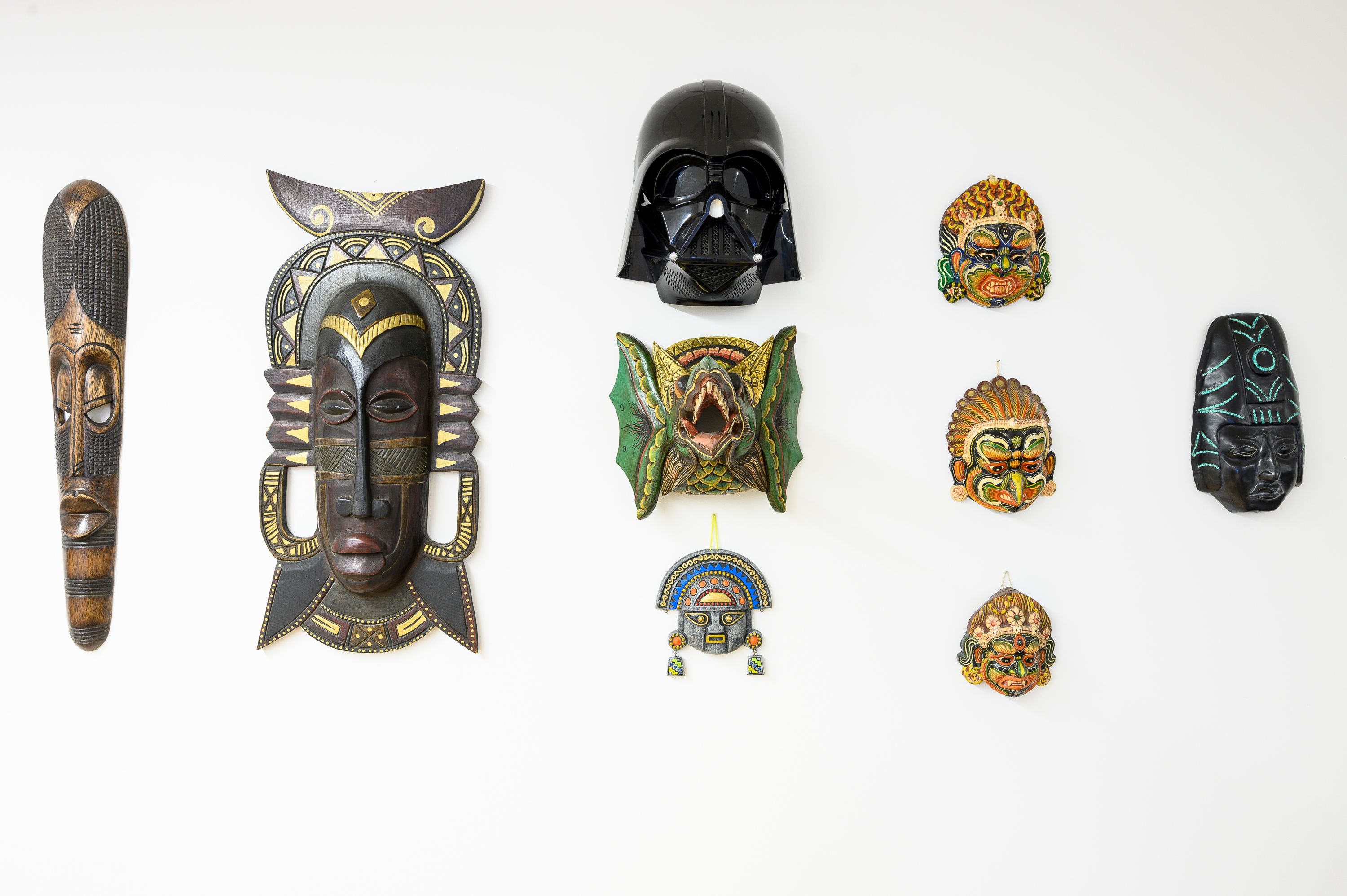 Le mur de masques de l'agence : des masques du monde entier, et un casque de Dark Vador