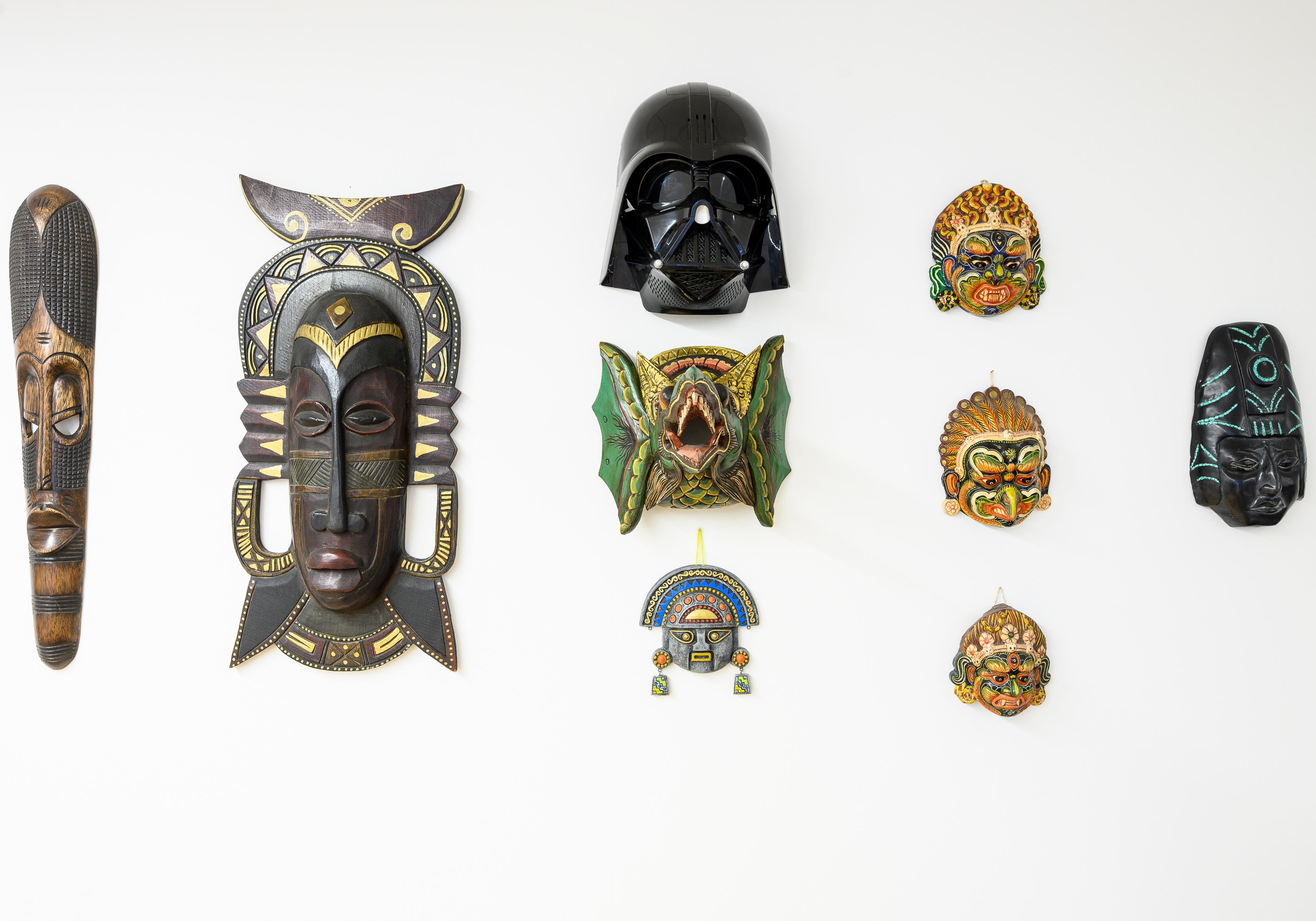 Le mur de masques de l'agence : des masques du monde entier, et un casque de Dark Vador