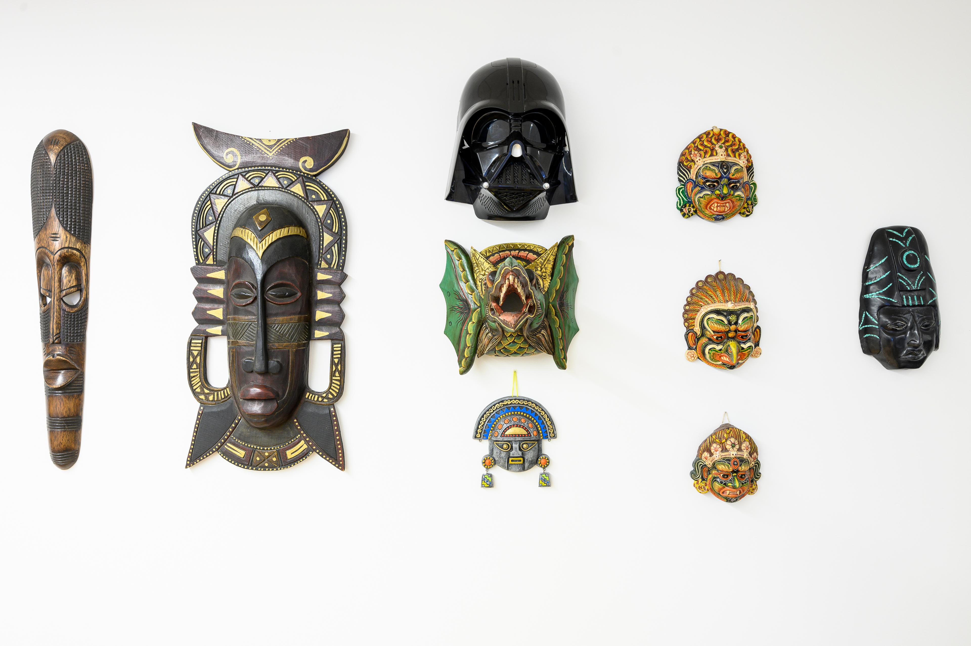 Le mur de masques de l'agence : des masques du monde entier, et un casque de Dark Vador