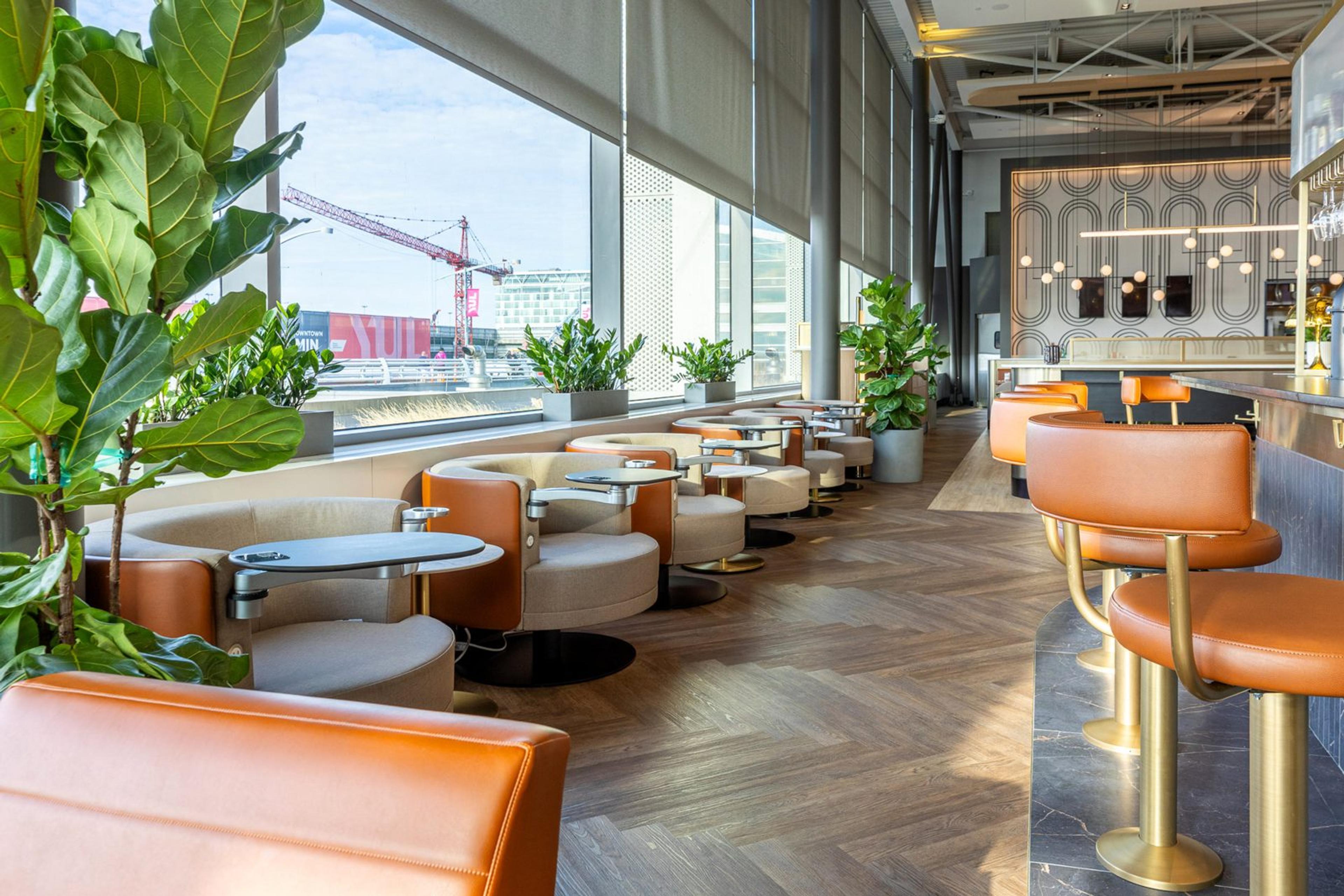 Des fauteuils le long des baies vitrées et des tabourets au bar du salon Aspire