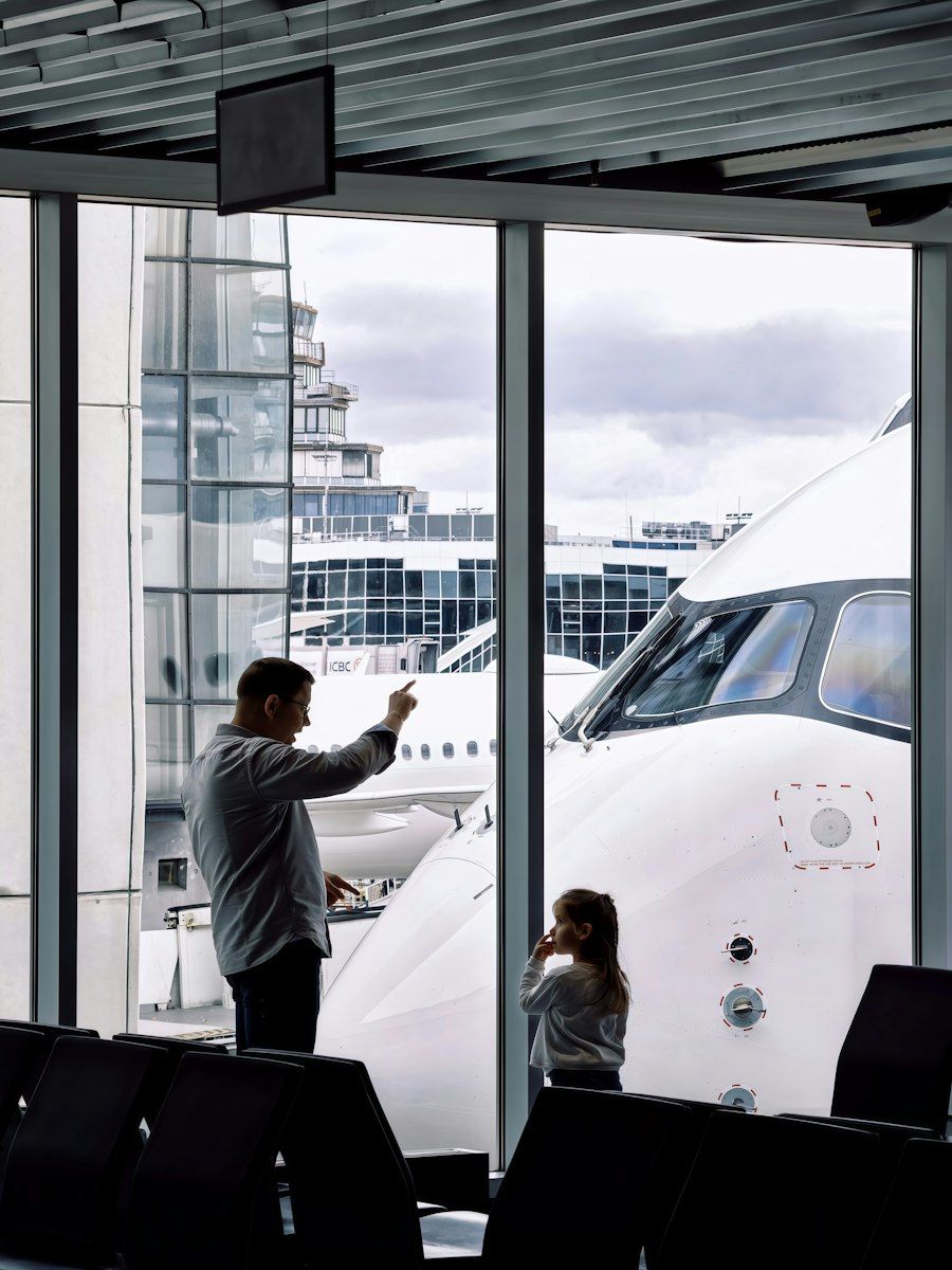 A father and daughter watching their plane from the gate