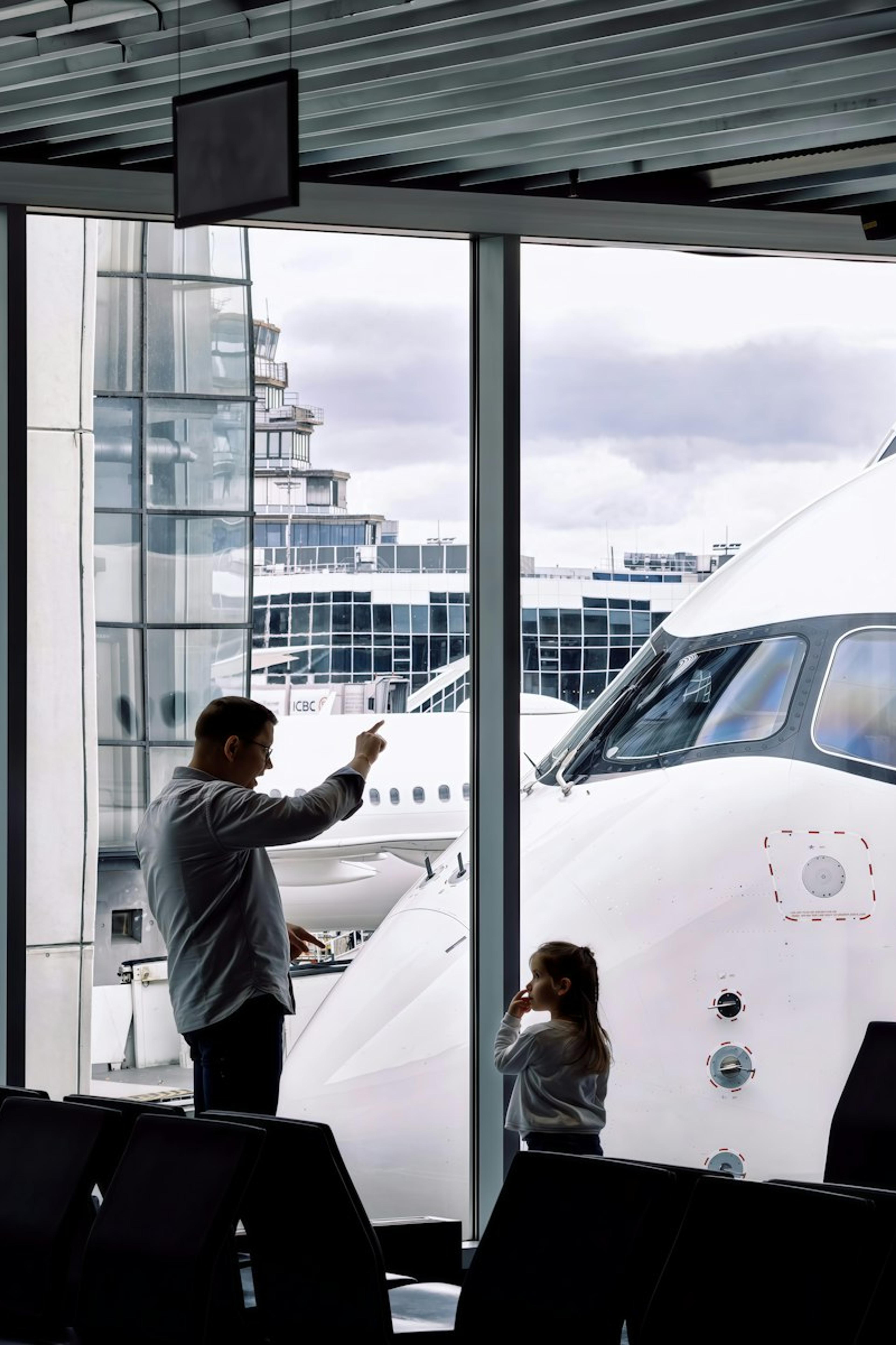 A father and daughter watching their plane from the gate