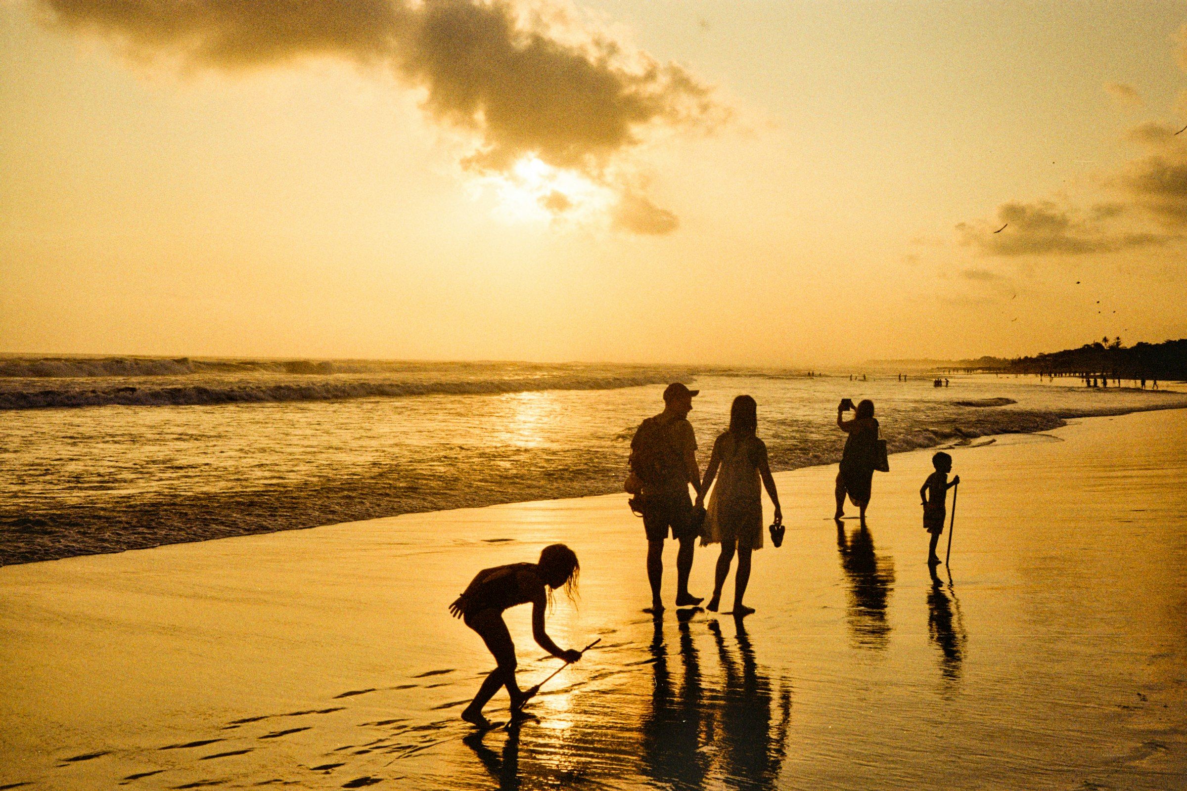 A family walking on the beach at sunset