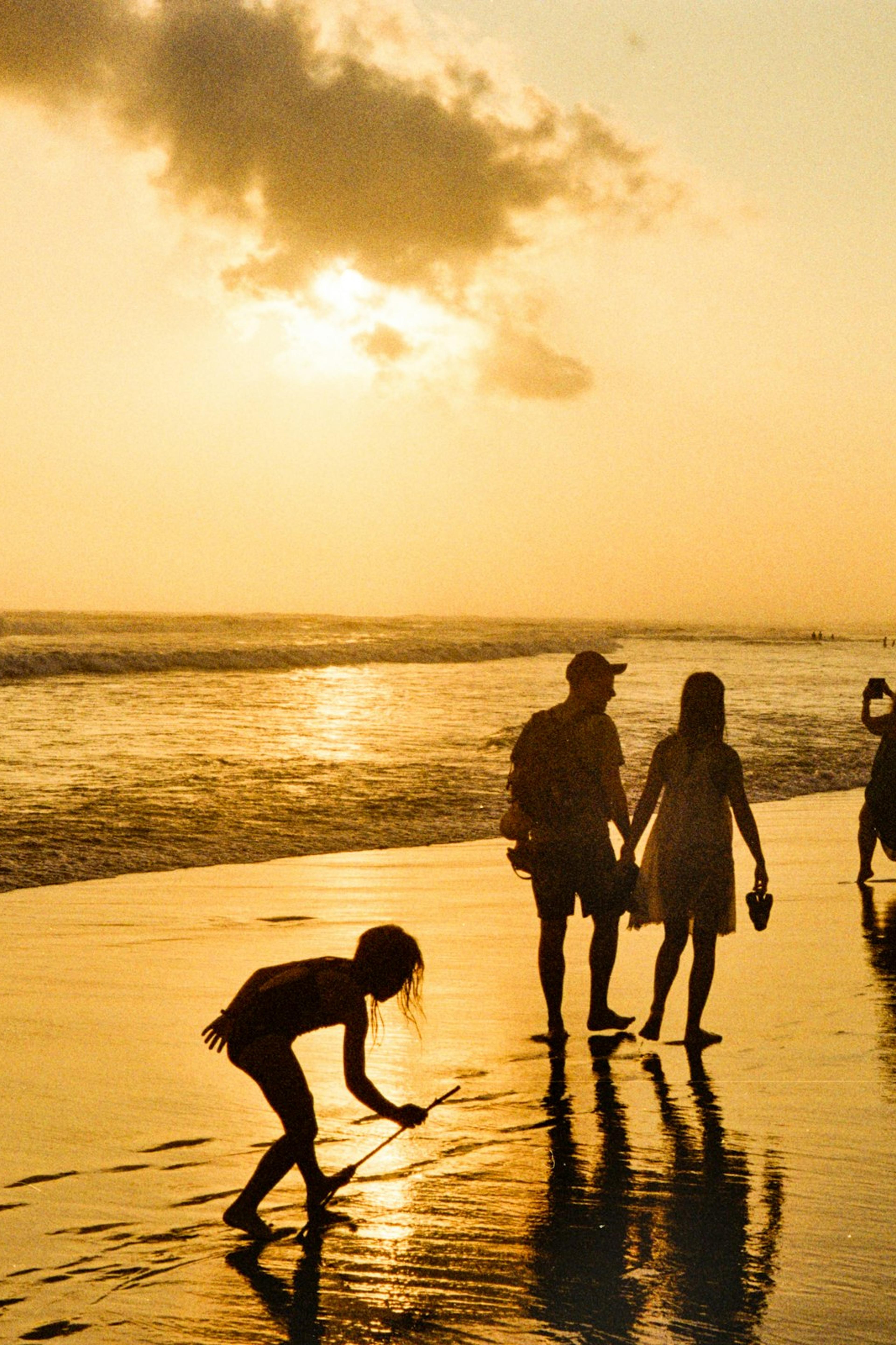 A family walking on the beach at sunset