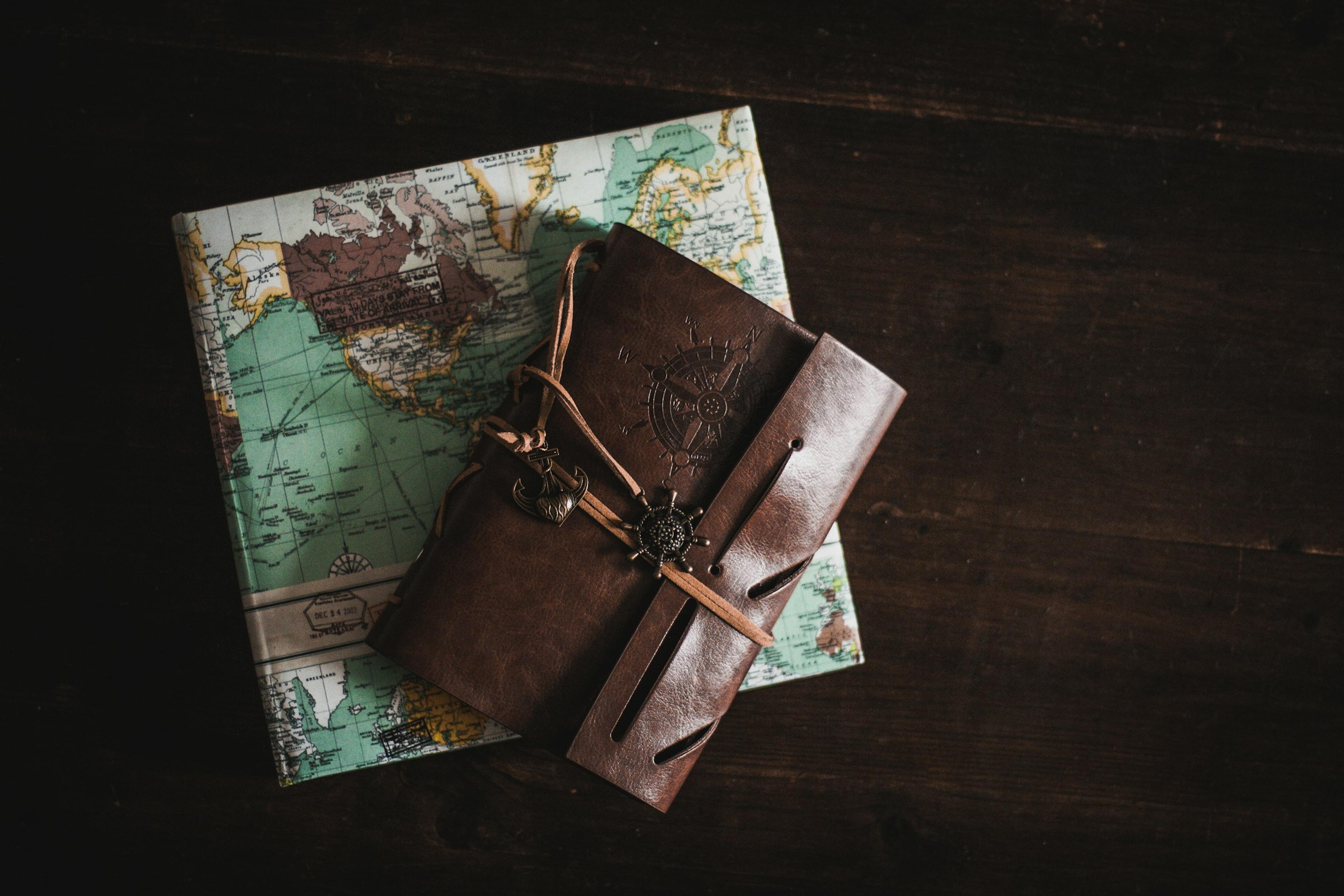 Un carnet de voyage en cuir, fermé par une lanière, posé sur une carte