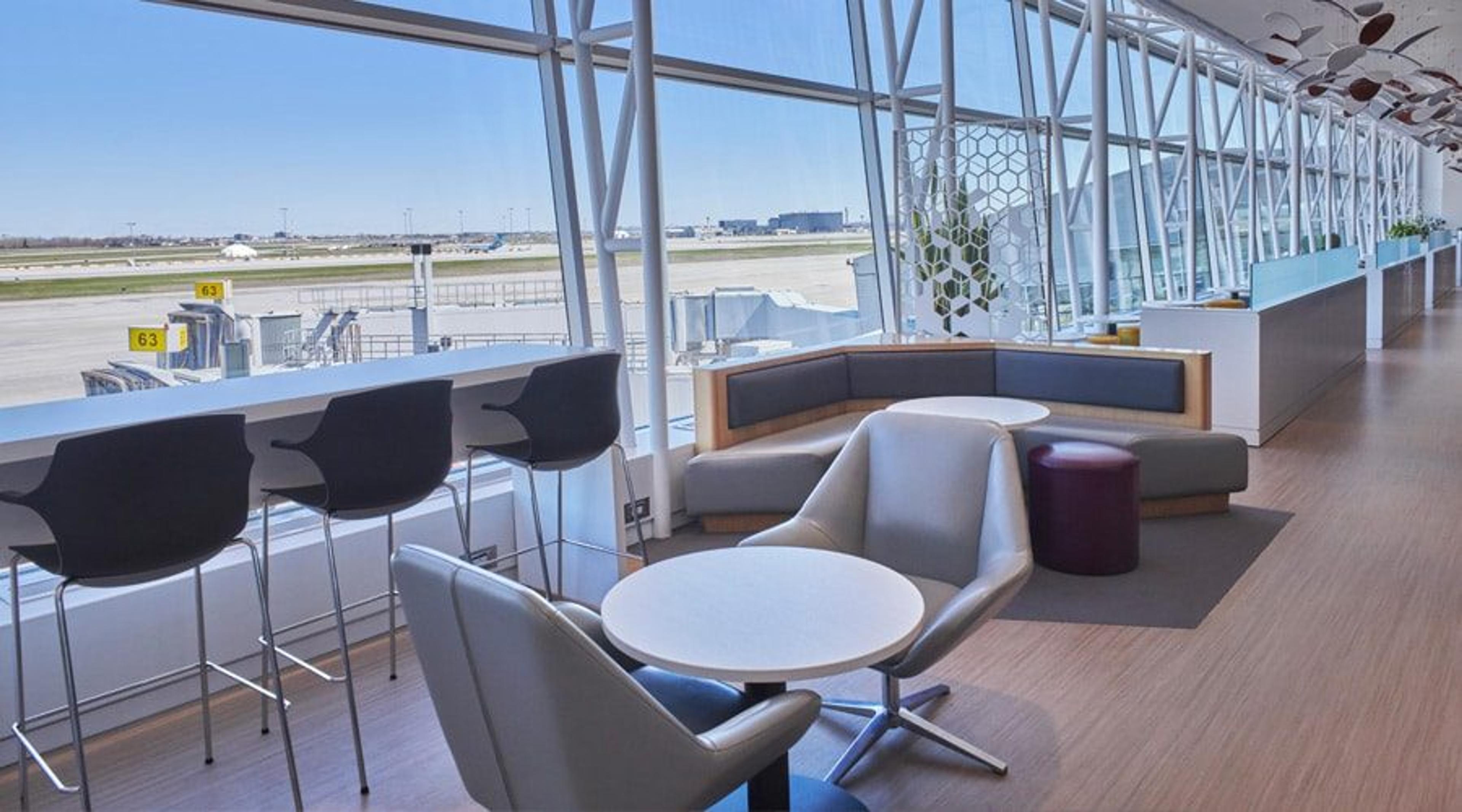 Des fauteuils et des tables hautes devant les baies vitrées du salon Odyssée