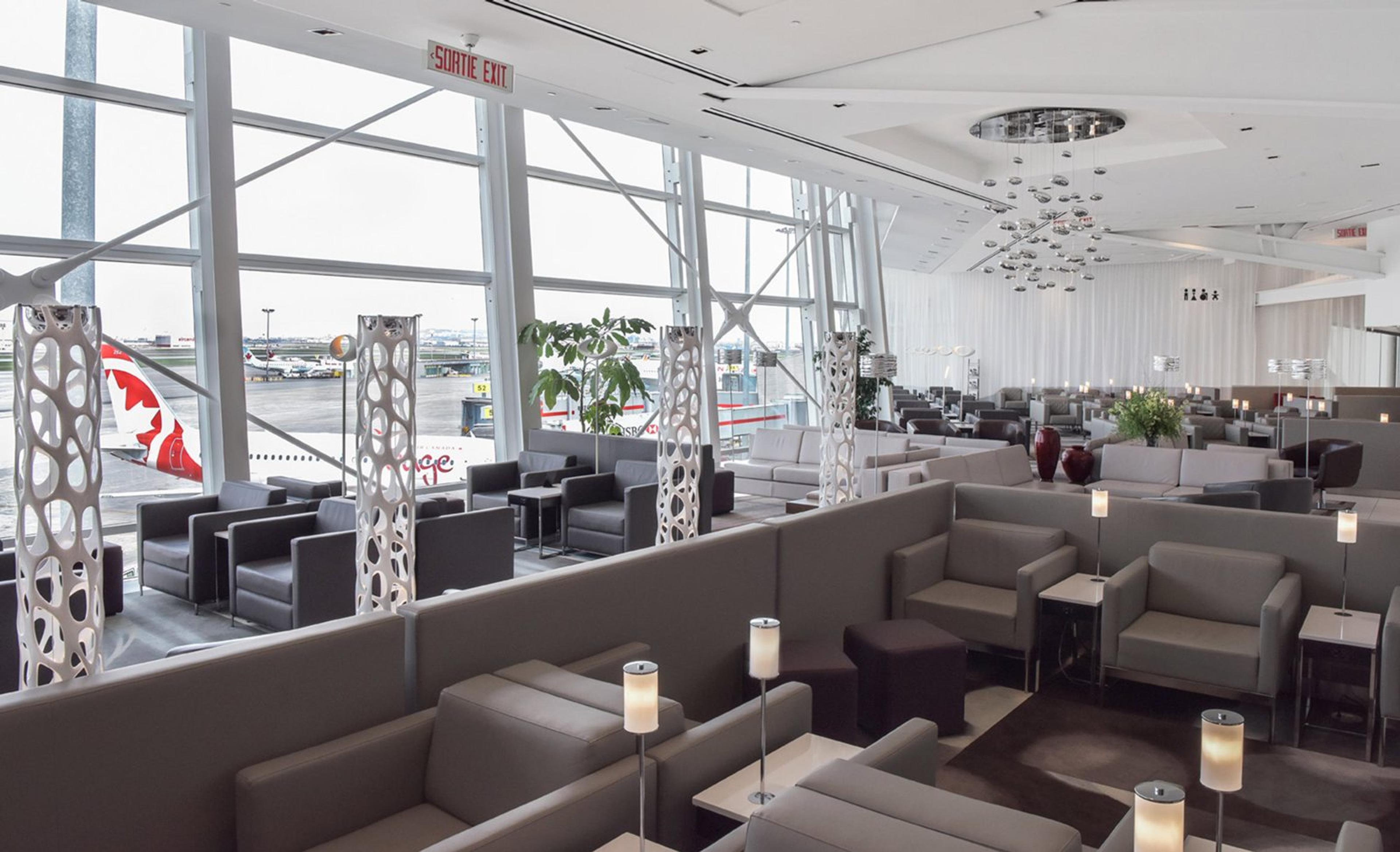 Le salon Banque Nationale, ses fauteuils gris et ses grandes baies vitrées donnant sur les avions