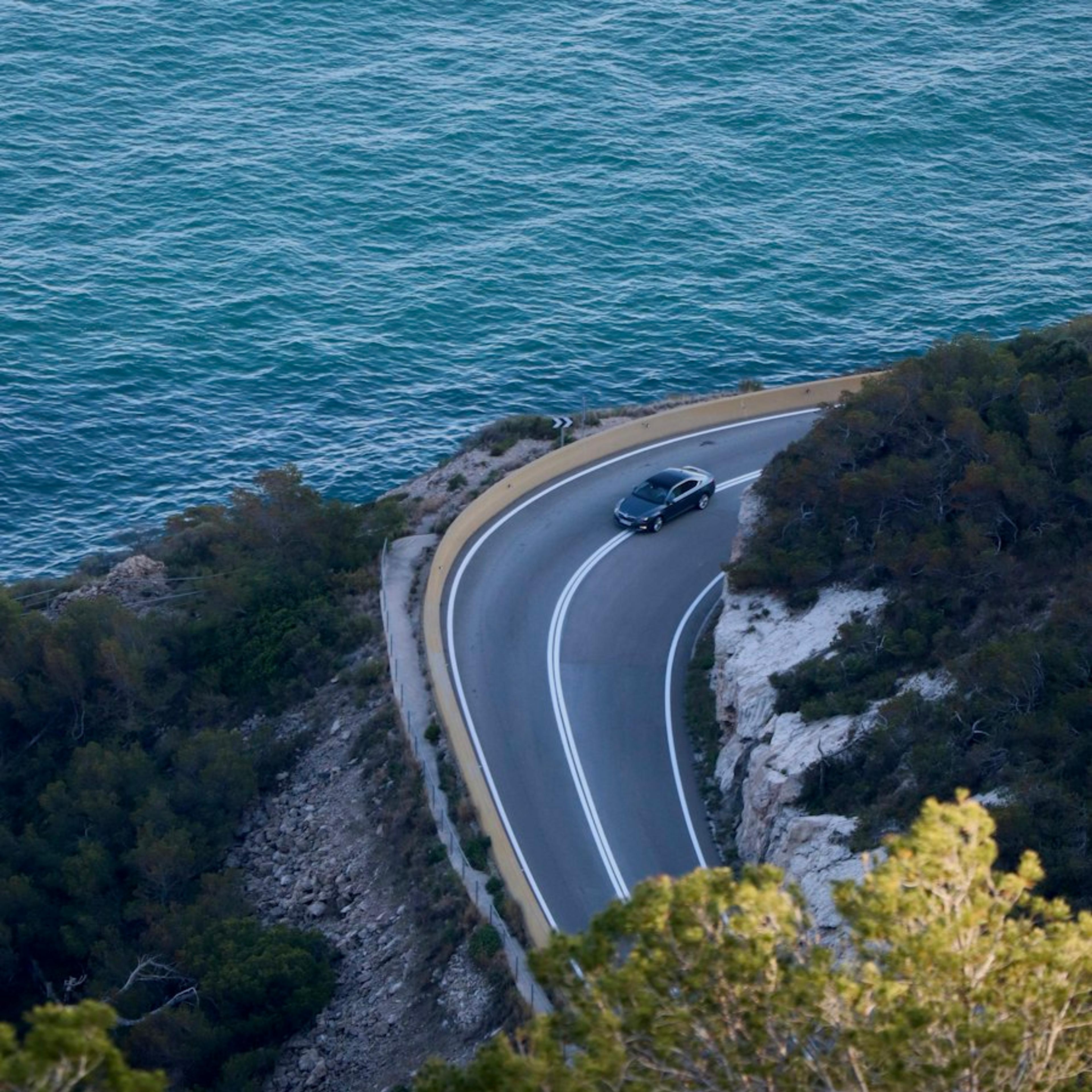 A car on a coastal road, seen from above