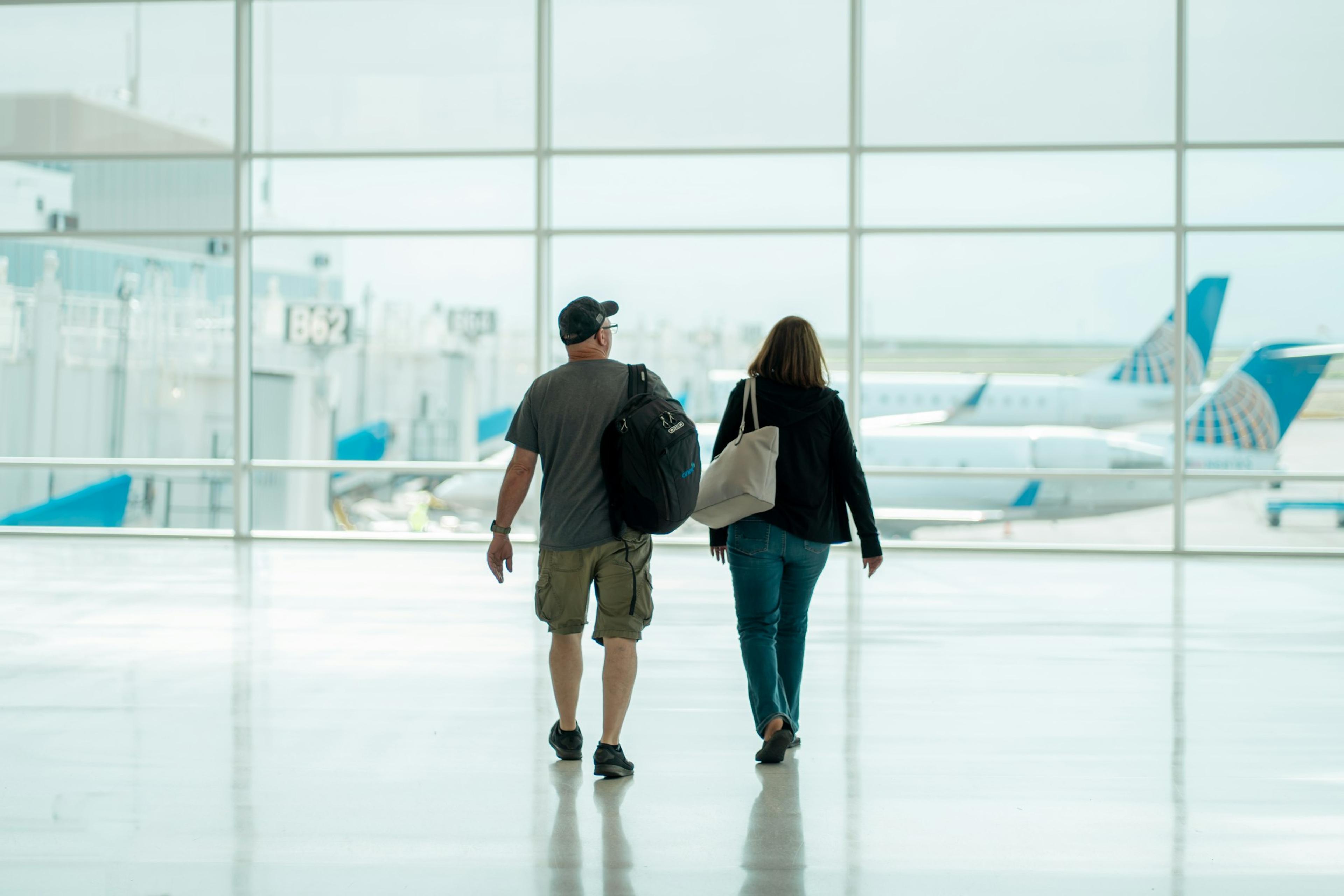 Un couple marche dans l'aérogare, les avions derrière les vitres