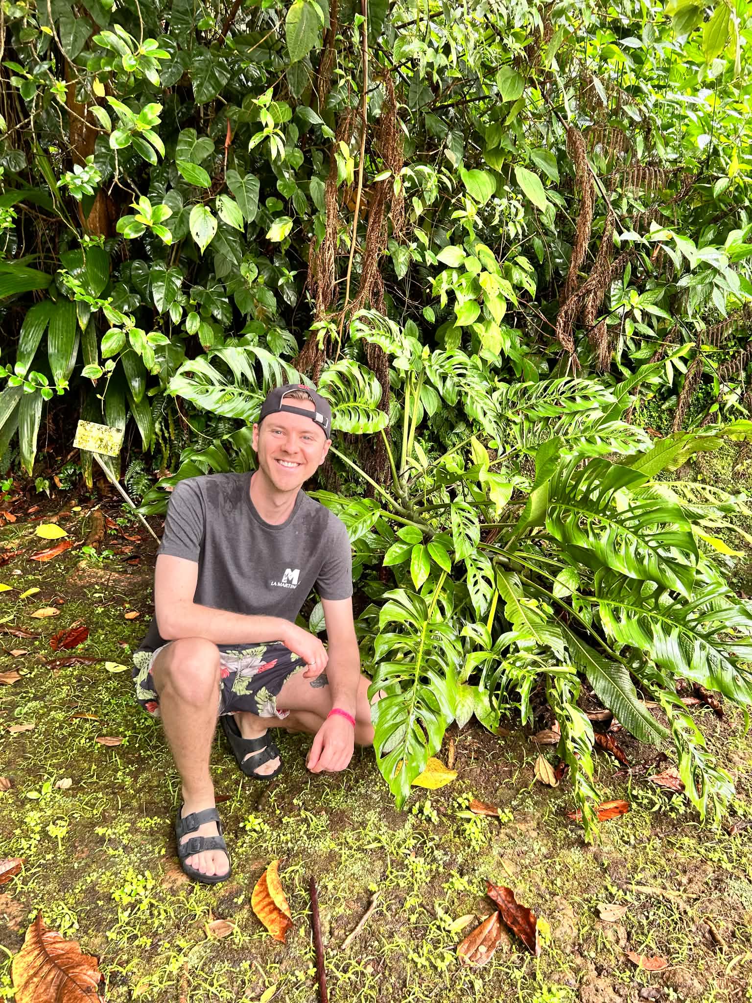 Jérémie Lesuise, souriant, accroupi devant une végétation tropicale
