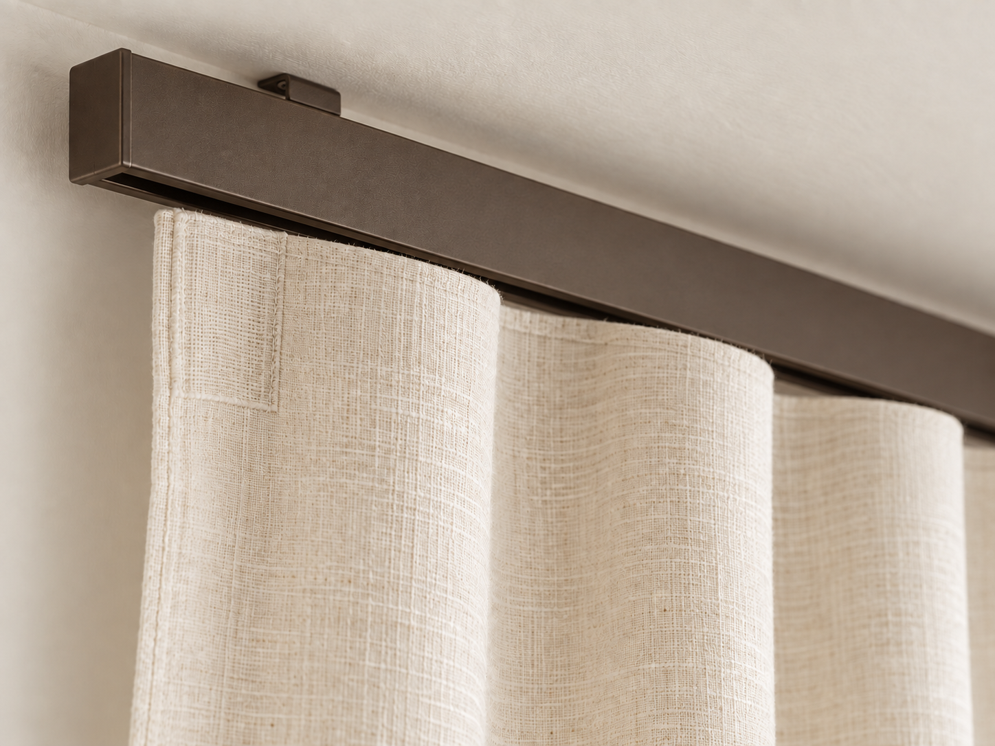 Close-up of a Bronze Architrac track and ivory linen curtain heading