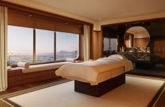 A panoramic bedroom with a broad sea-facing window and marble bathroom beyond.