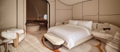 A bedroom with rounded furniture and sculpted wall panels.