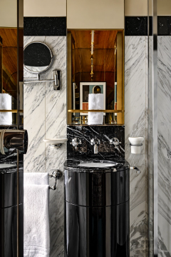 Polychrome marble and a rounded vanity create a compact bathroom composition.