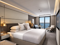 A softly furnished bedroom with terrace doors and a sea view.