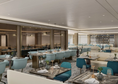 A light-filled restaurant with pale blue seating and carefully set tables.