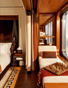 Polished wood, a window-side daybed and a chessboard in a warm suite interior.