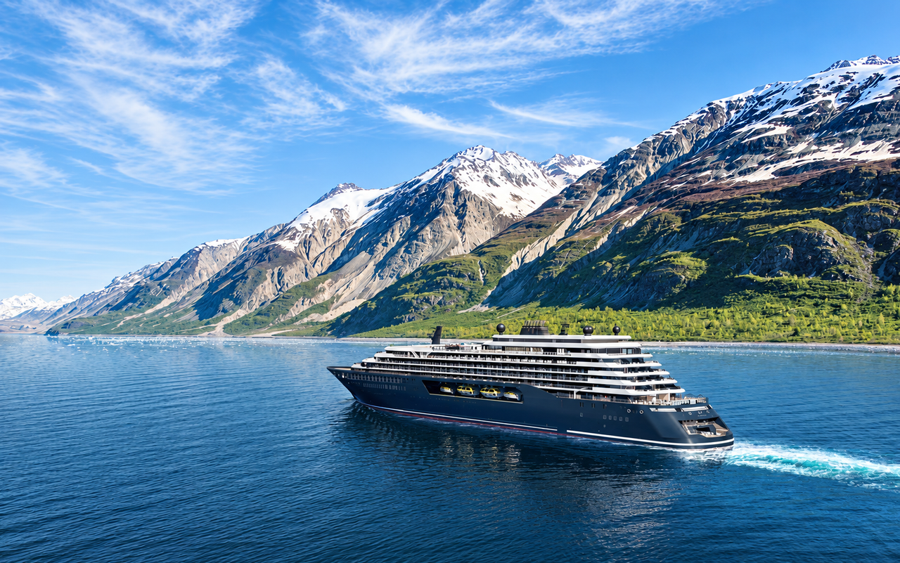 A dark-hulled yacht against a mountainous coastal landscape.
