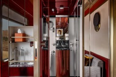 Red lacquer, reflective walls and marble details in a cabin bathroom.