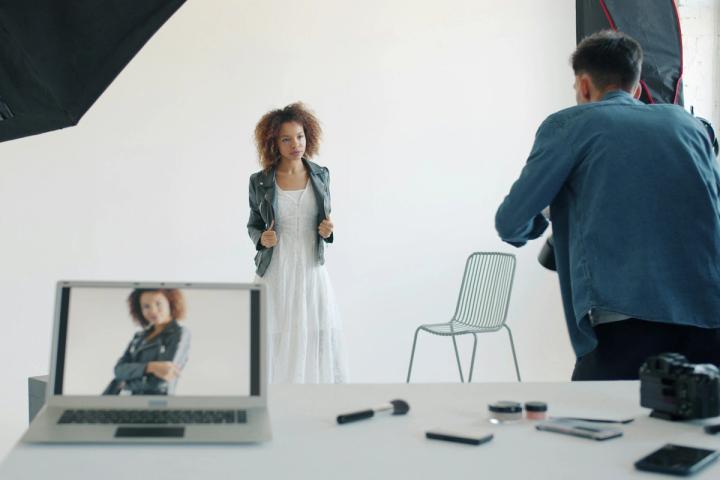 Model posing in studio with photographer and equipment