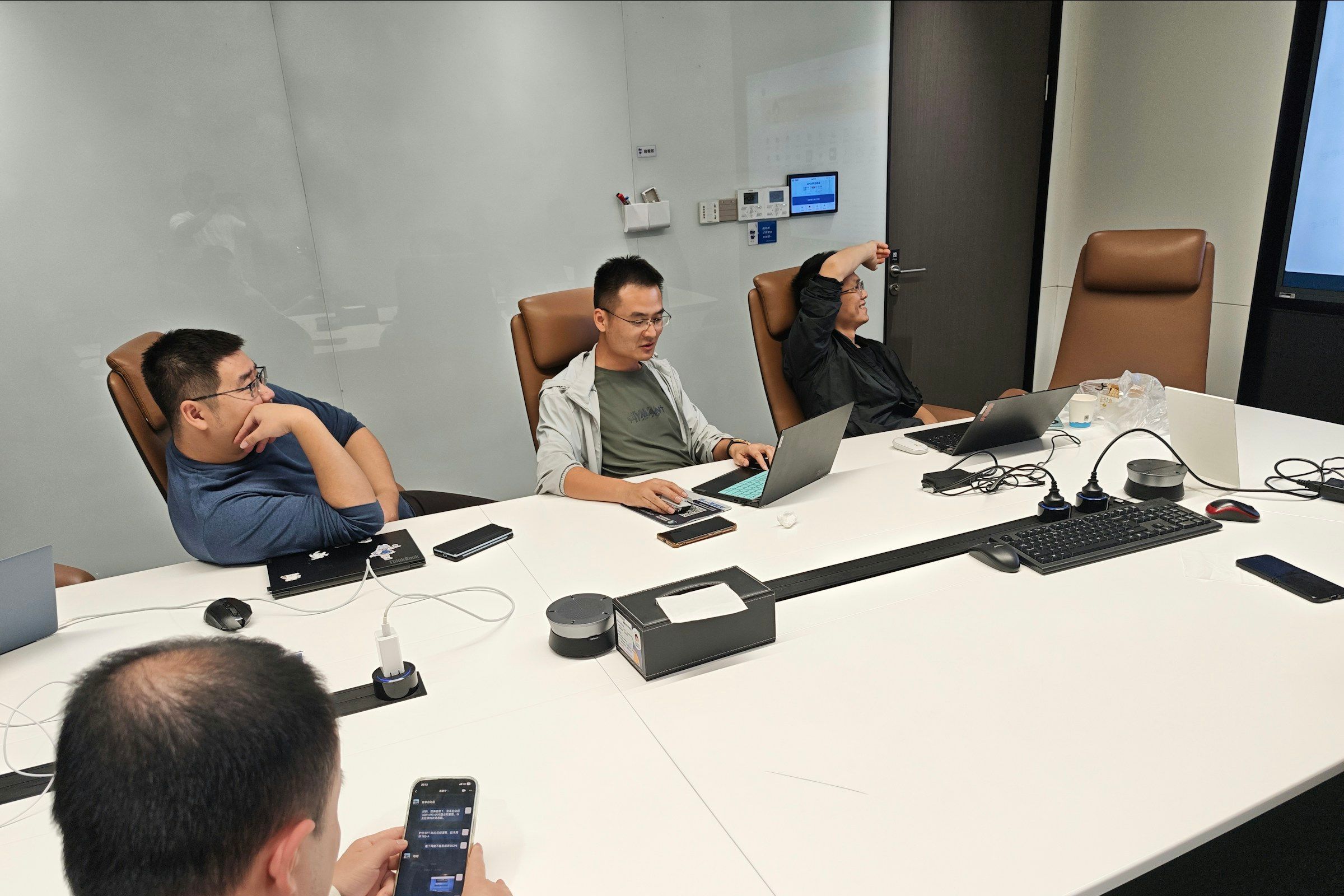 Four men in a meeting room with laptops.