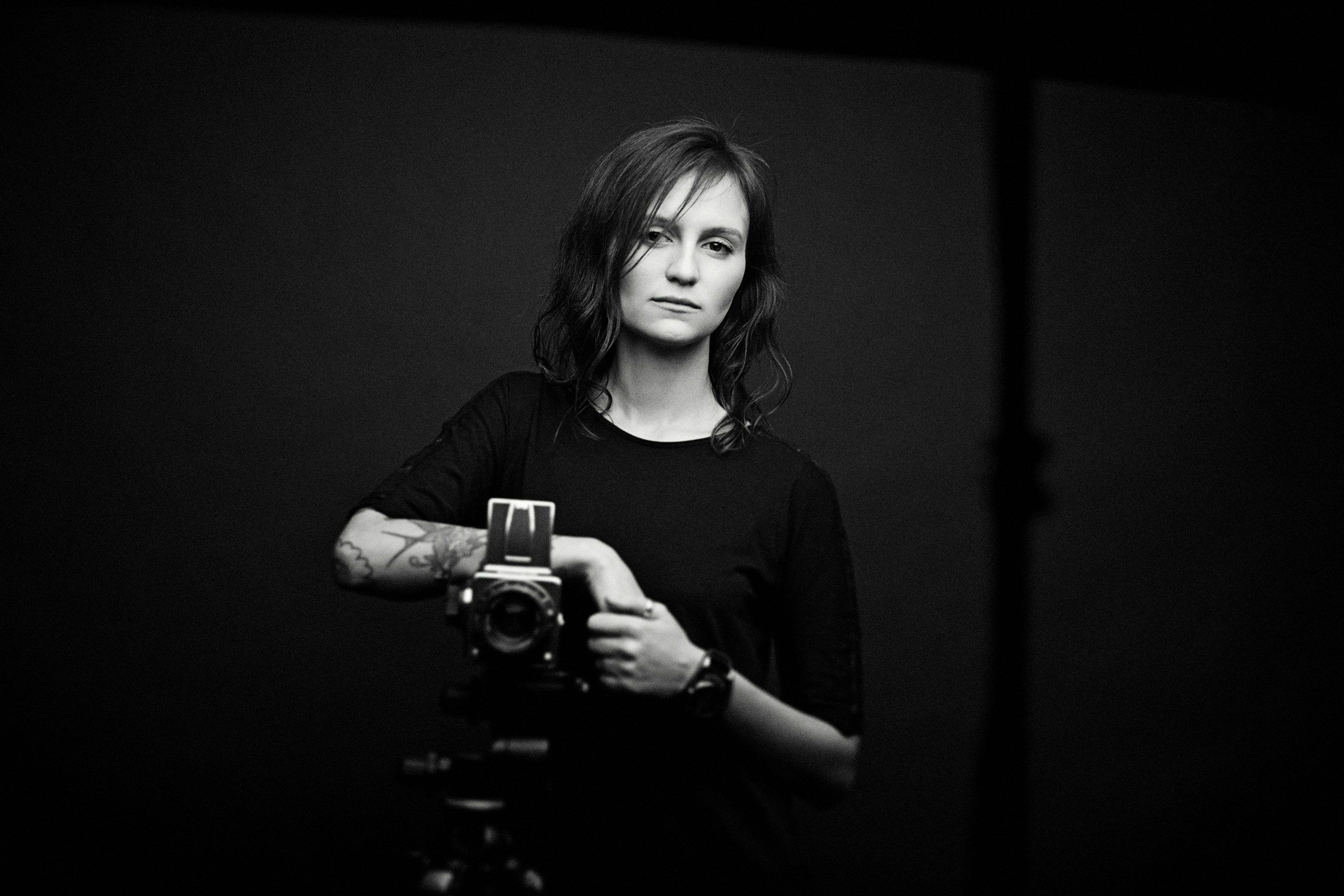 a black and white photo of a woman holding a camera
