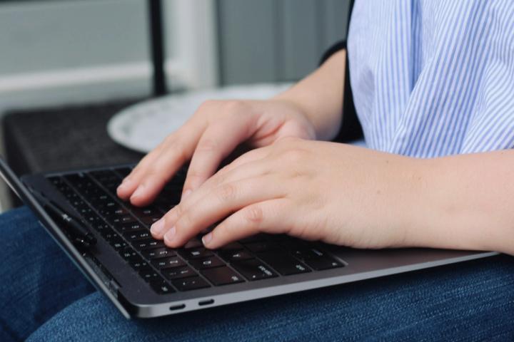 Person types on a laptop keyboard.