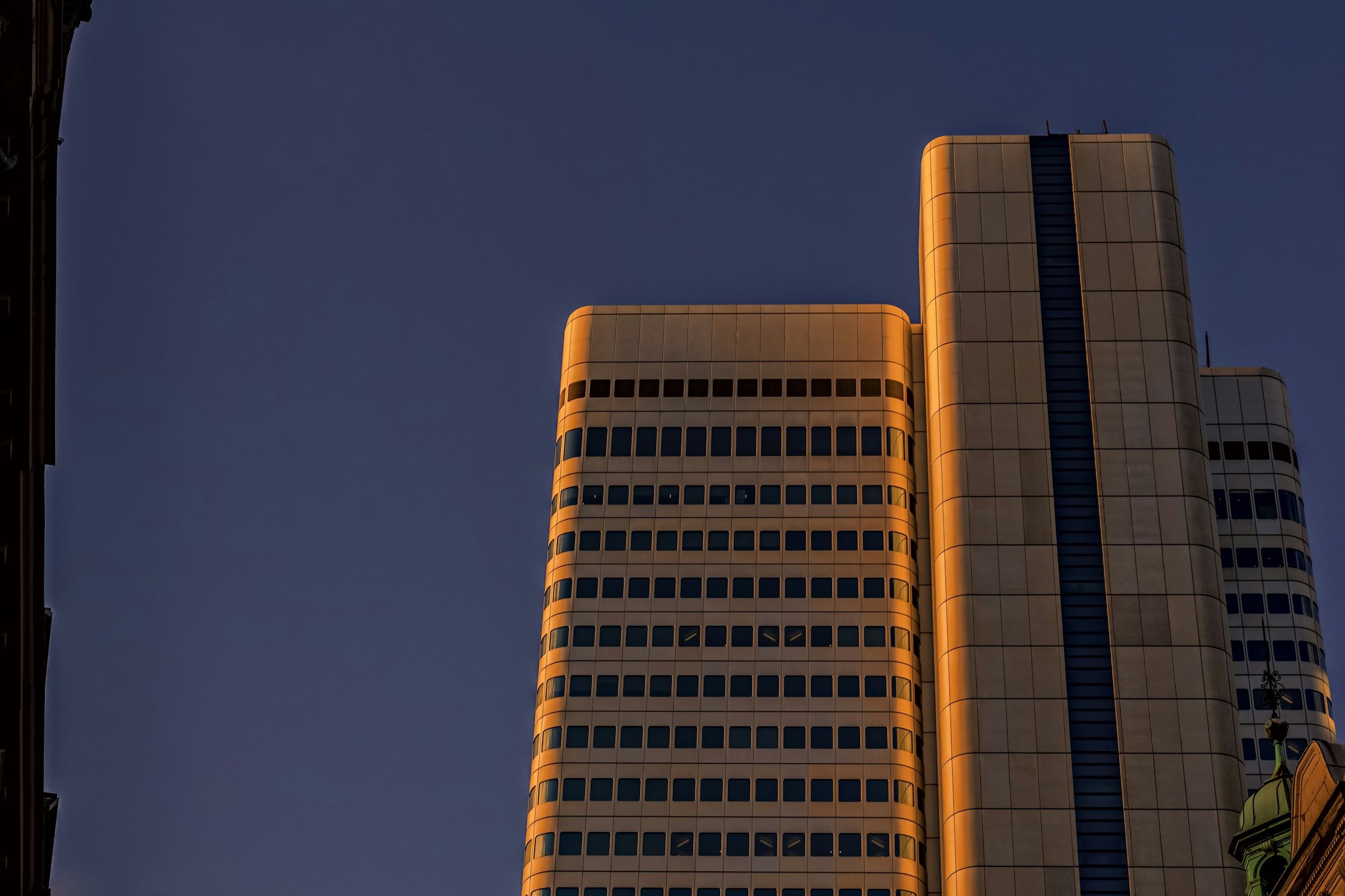 Skyscrapers are lit by sunlight against a blue sky