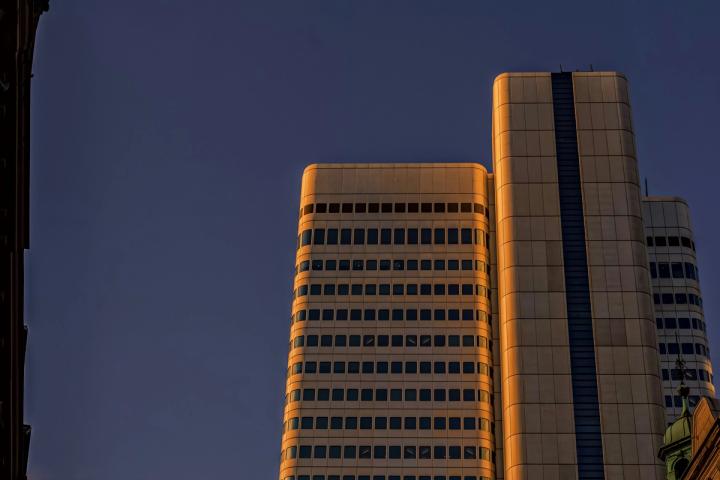 Skyscrapers are lit by sunlight against a blue sky