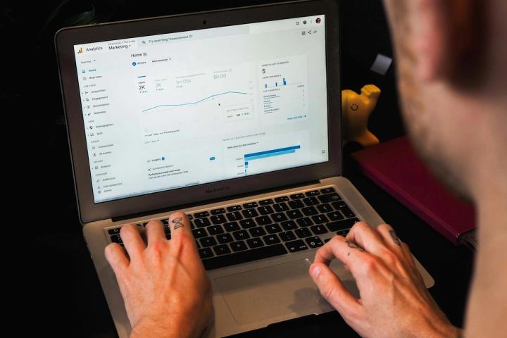 person using macbook pro on black table